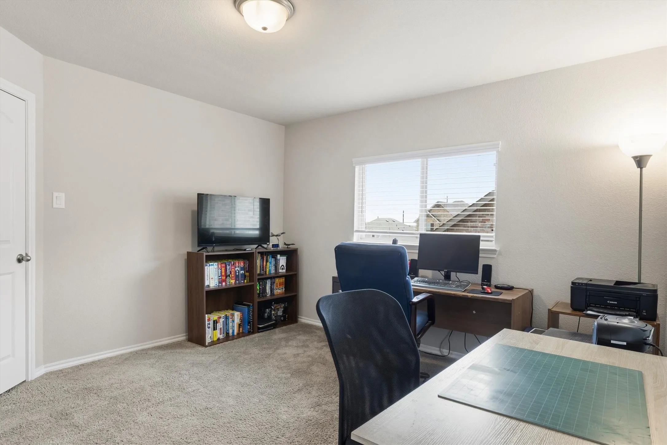 Well-lit room featuring light-colored walls, ceiling-mounted lighting, and carpet flooring