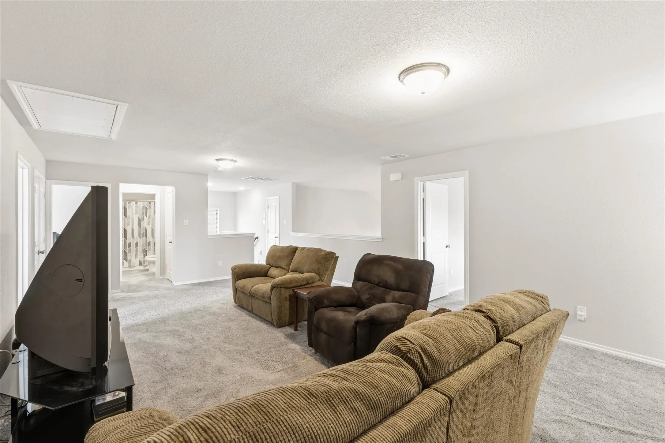 Spacious secondary living area featuring light gray wall paint, light gray carpeting, and white trim