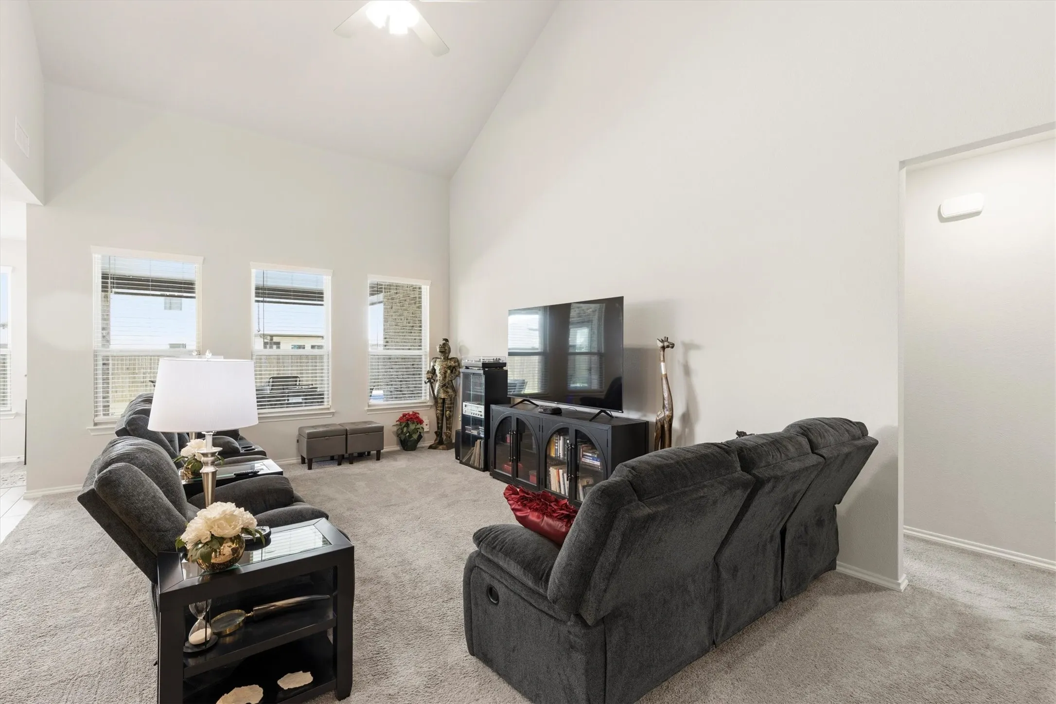 Spacious living area featuring a vaulted ceiling and light gray carpeting