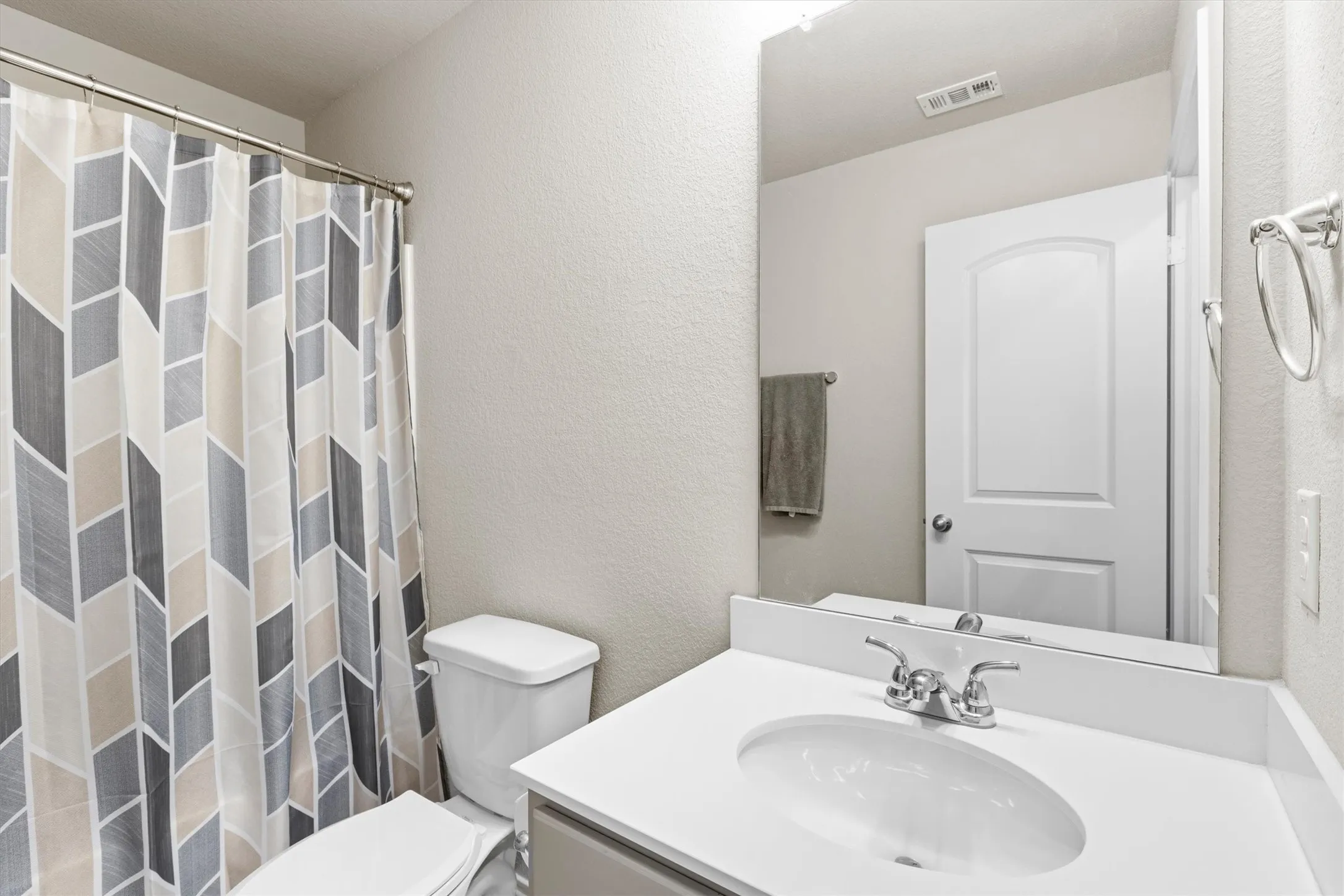 Bathroom featuring a single vanity with an integrated sink, polished chrome faucet, and a large wall-mounted mirror