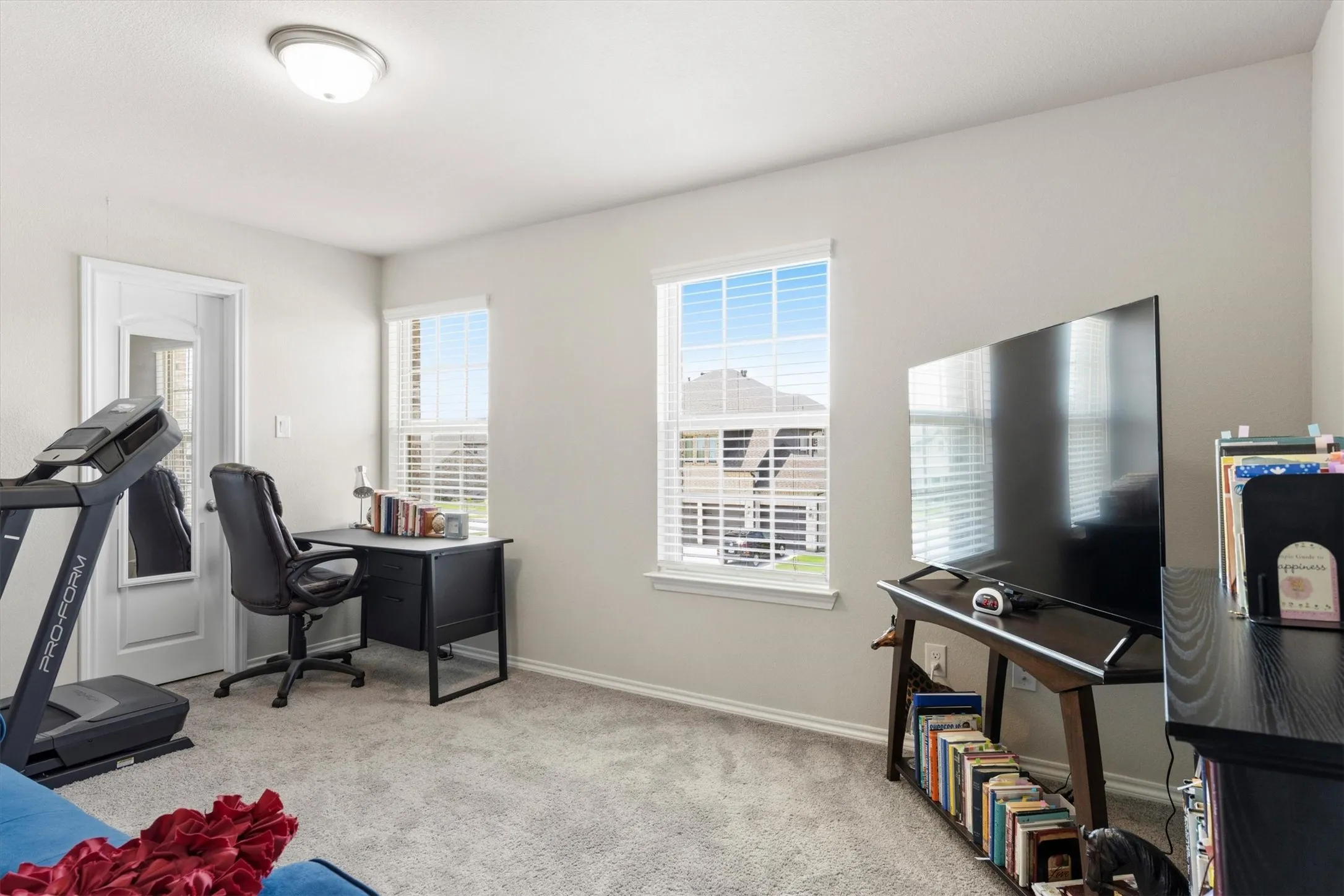 Carpeted room featuring two windows with white blinds, a white paneled door, light gray walls, and a flush mount ceiling light fixture