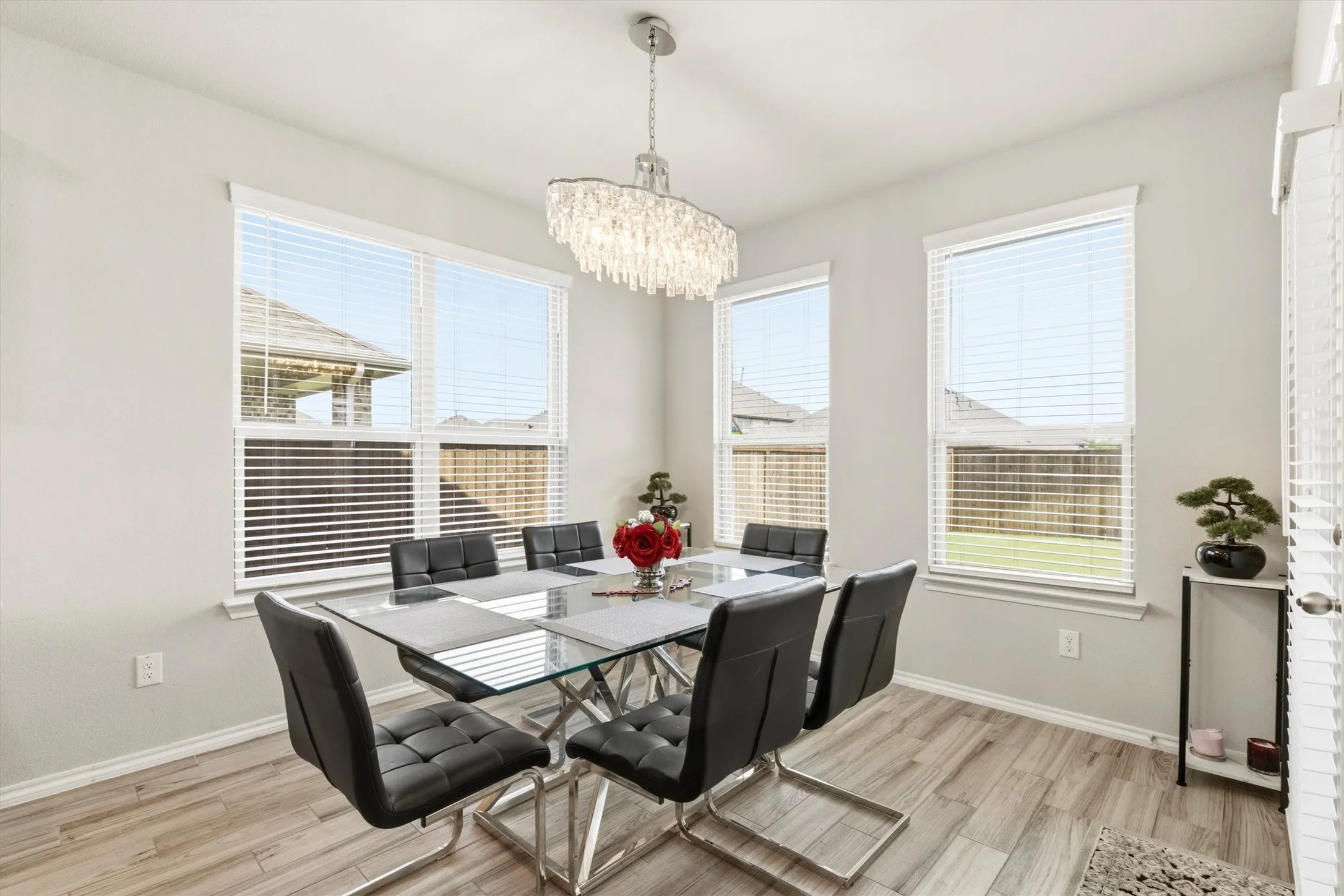 Spacious dining area featuring wood-finish flooring and multiple windows with blinds