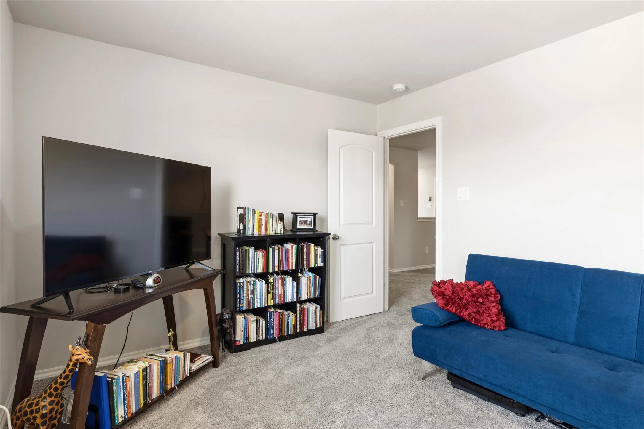 Carpeted room with light neutral wall paint, a white interior door, and a built-in ceiling light