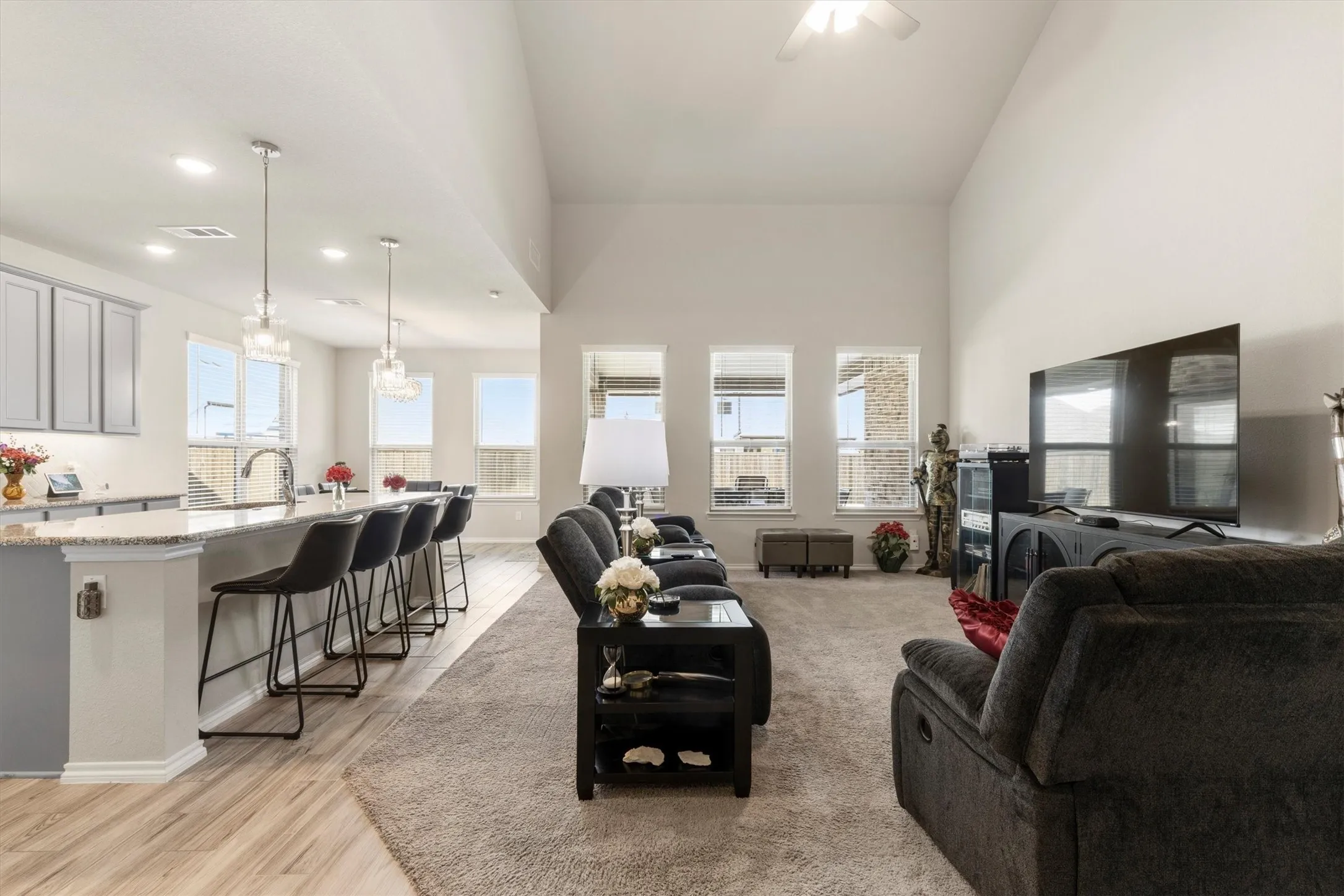 Open-concept living area featuring a vaulted ceiling and an integrated kitchen with gray cabinetry