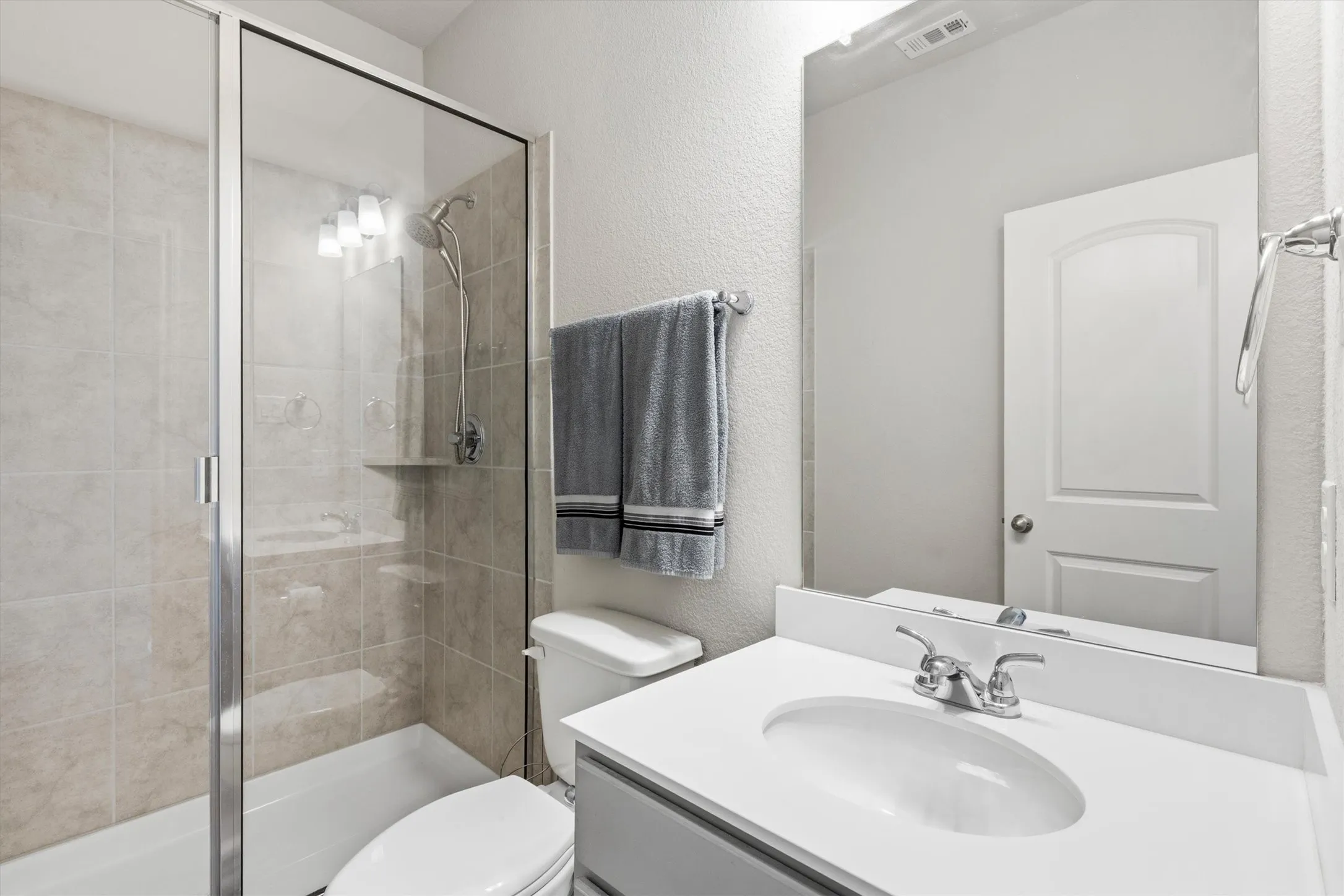 Bathroom featuring a glass-enclosed shower with subway tile surround, white bathtub, single vanity with integrated sink, and chrome fixtures