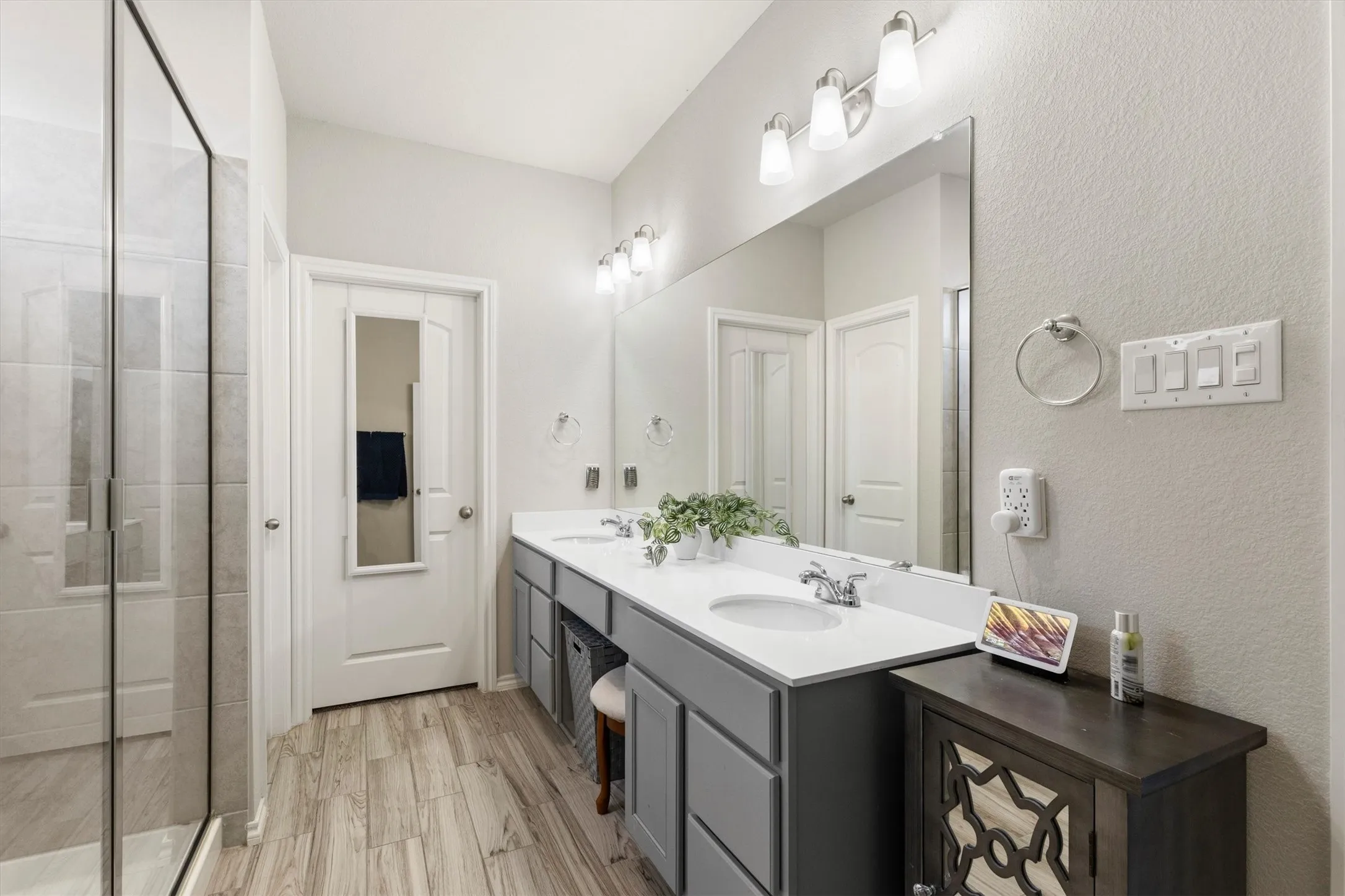 Spacious bathroom featuring a dual vanity with white countertops, grey cabinetry, and chrome fixtures