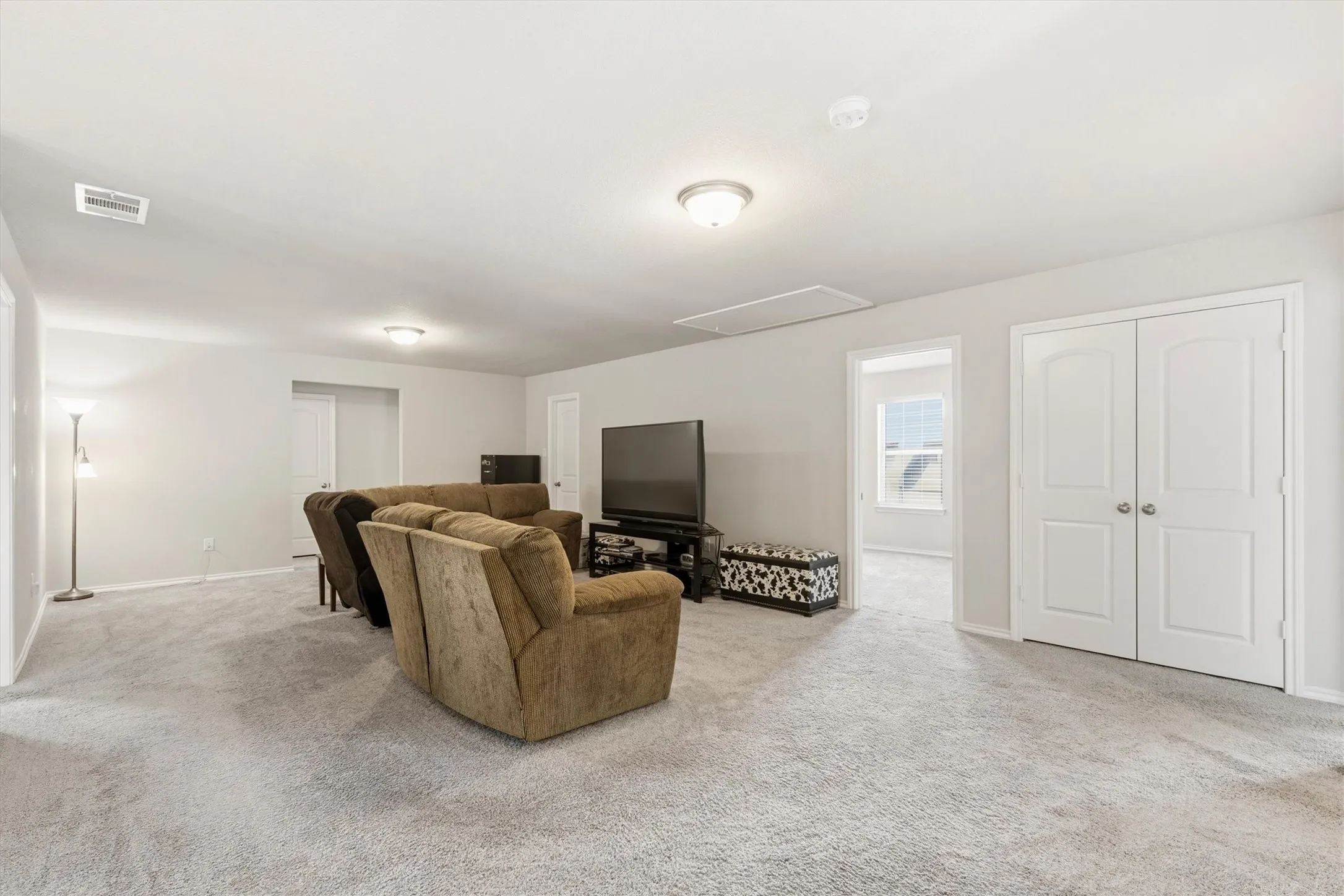 Spacious carpeted room featuring light gray walls, white trim, and a ceiling-mounted light fixture