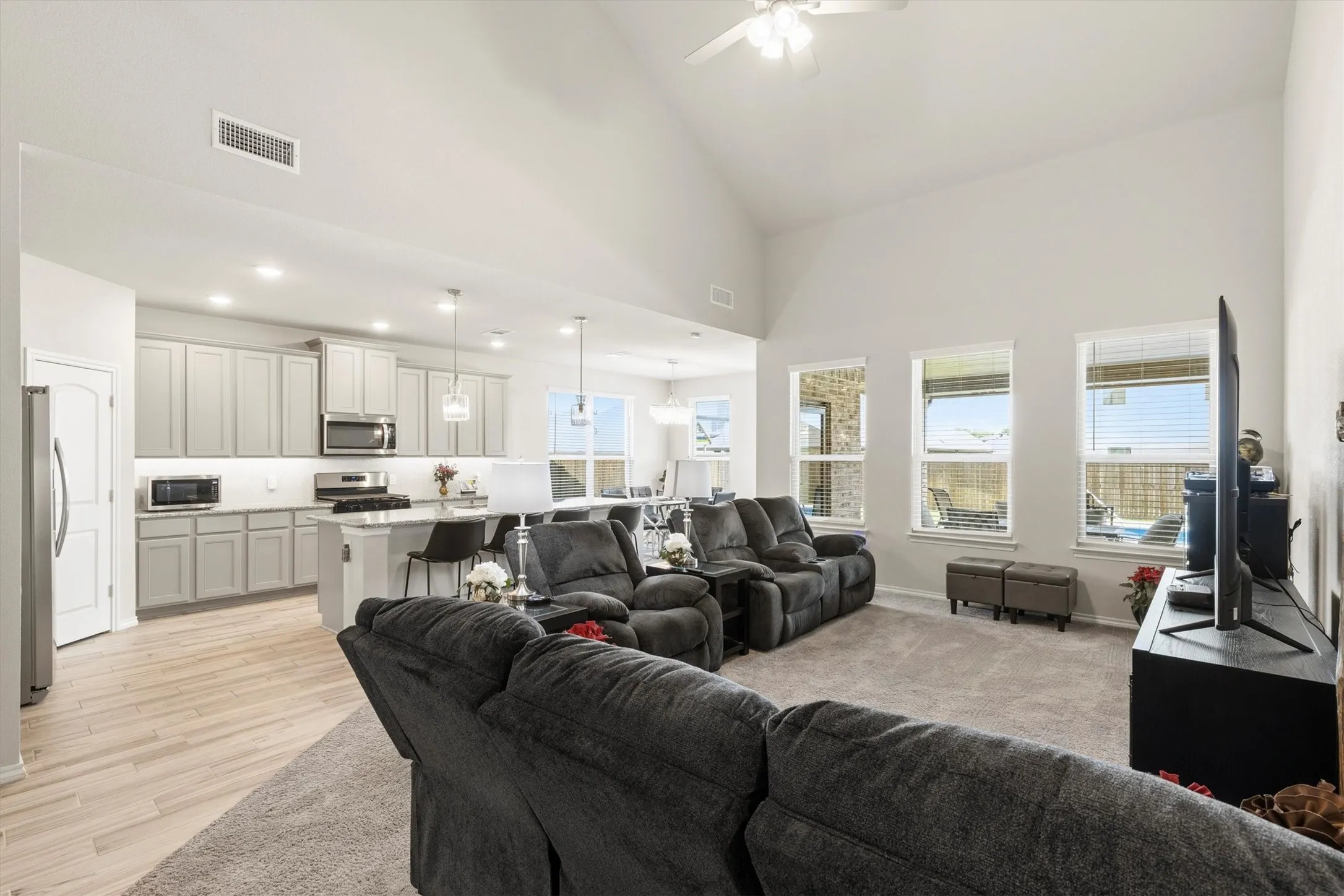 Spacious living area featuring a vaulted ceiling and carpet flooring