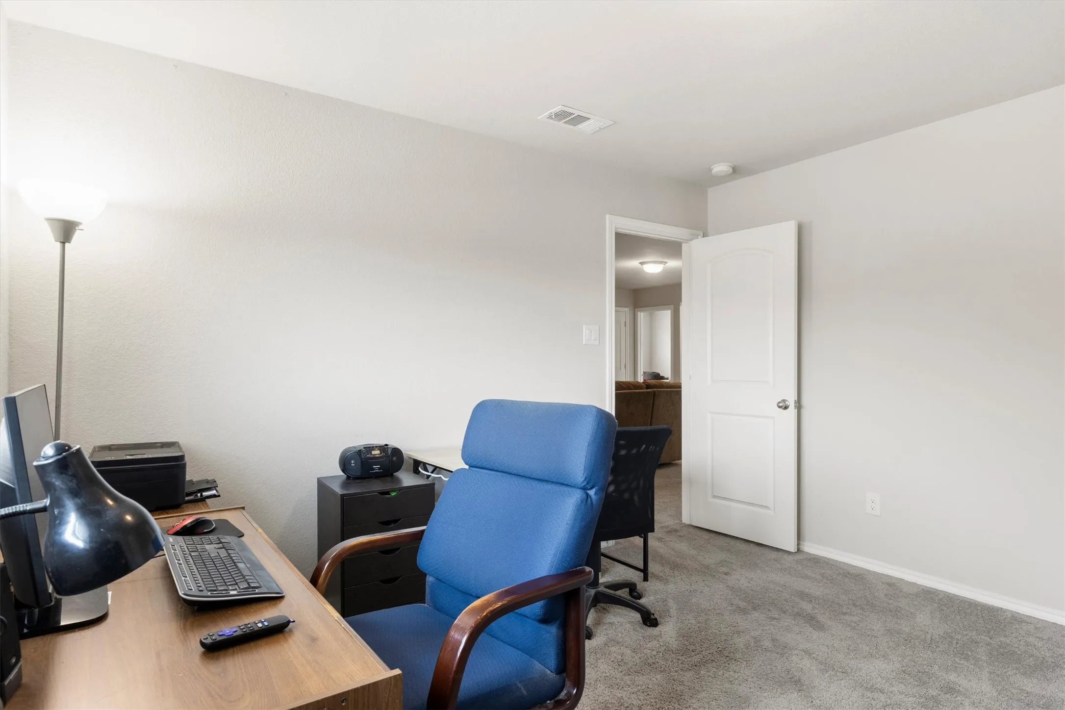 Carpeted room with light neutral walls, white baseboards, and a white interior door with a silver-tone handle