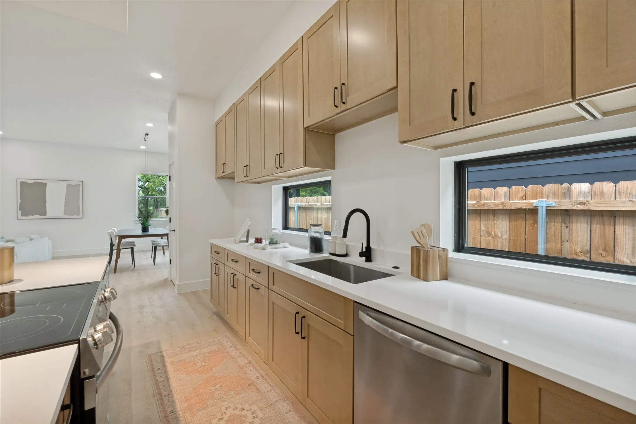 Contemporary kitchen featuring light wood-finish cabinetry, white countertops, and stainless steel appliances