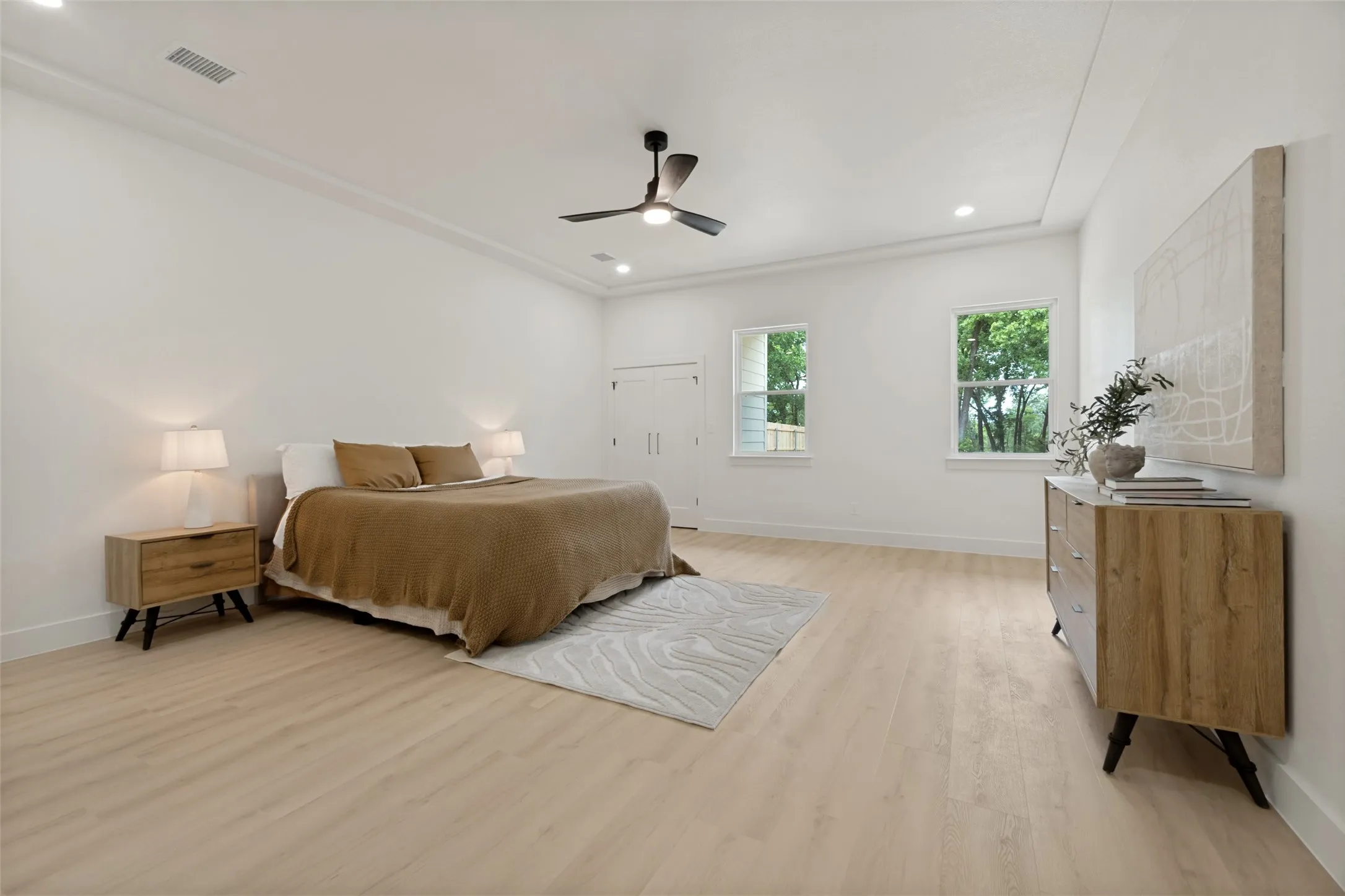 Spacious room featuring light wood-finish flooring, crisp white walls, and a recessed ceiling