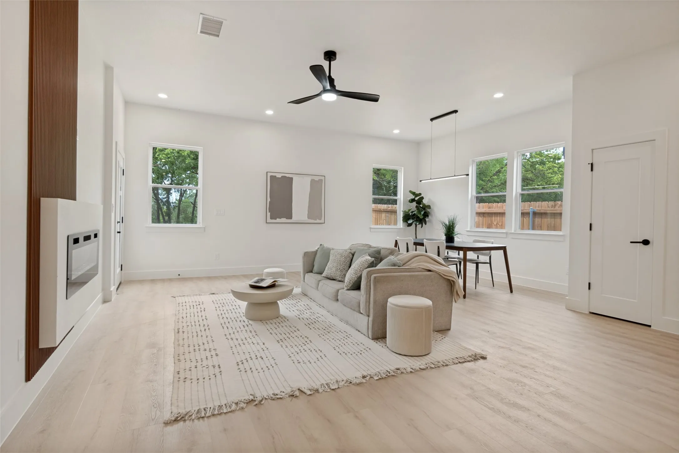 Open-concept living and dining area featuring light wood-finish flooring, a contemporary ceiling fan, and recessed lighting