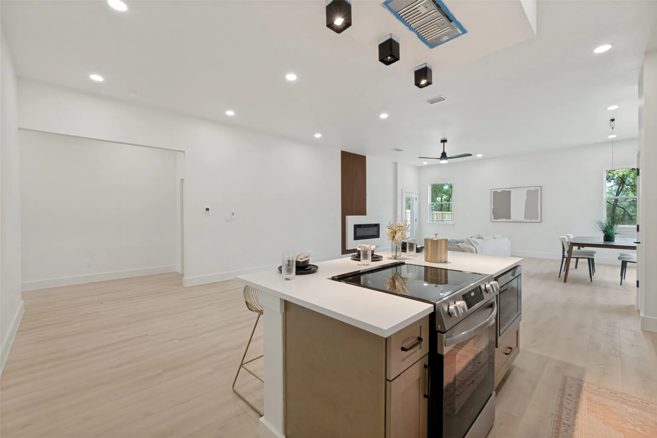 Expansive kitchen island with a built-in electric range and stainless steel oven, complemented by light wood-finish flooring