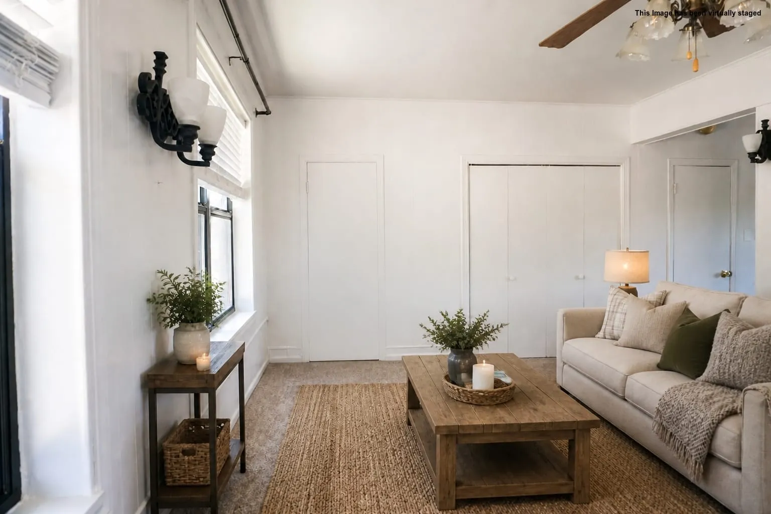 Living area featuring light-toned flooring, white walls, and a ceiling fan with integrated lighting