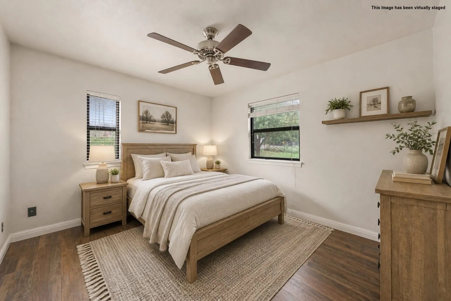 Wood-finish flooring with light-toned walls, ceiling fan with brown blades, and two windows with horizontal blinds