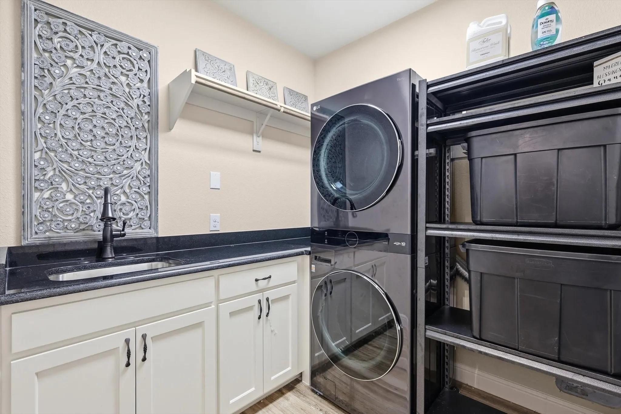 Laundry area featuring a dark countertop with an integrated sink and a black faucet