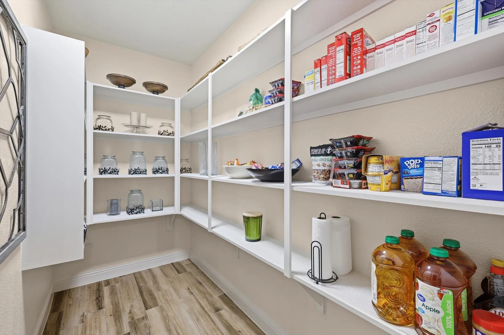 Dedicated pantry featuring extensive white shelving, wood-finish flooring, and neutral wall tones