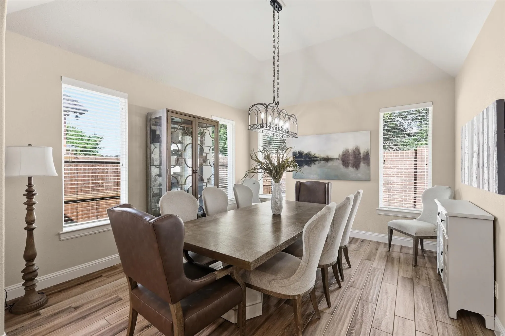 Dining space featuring high vaulted ceilings, light wood-finish flooring, and multiple windows with white blinds