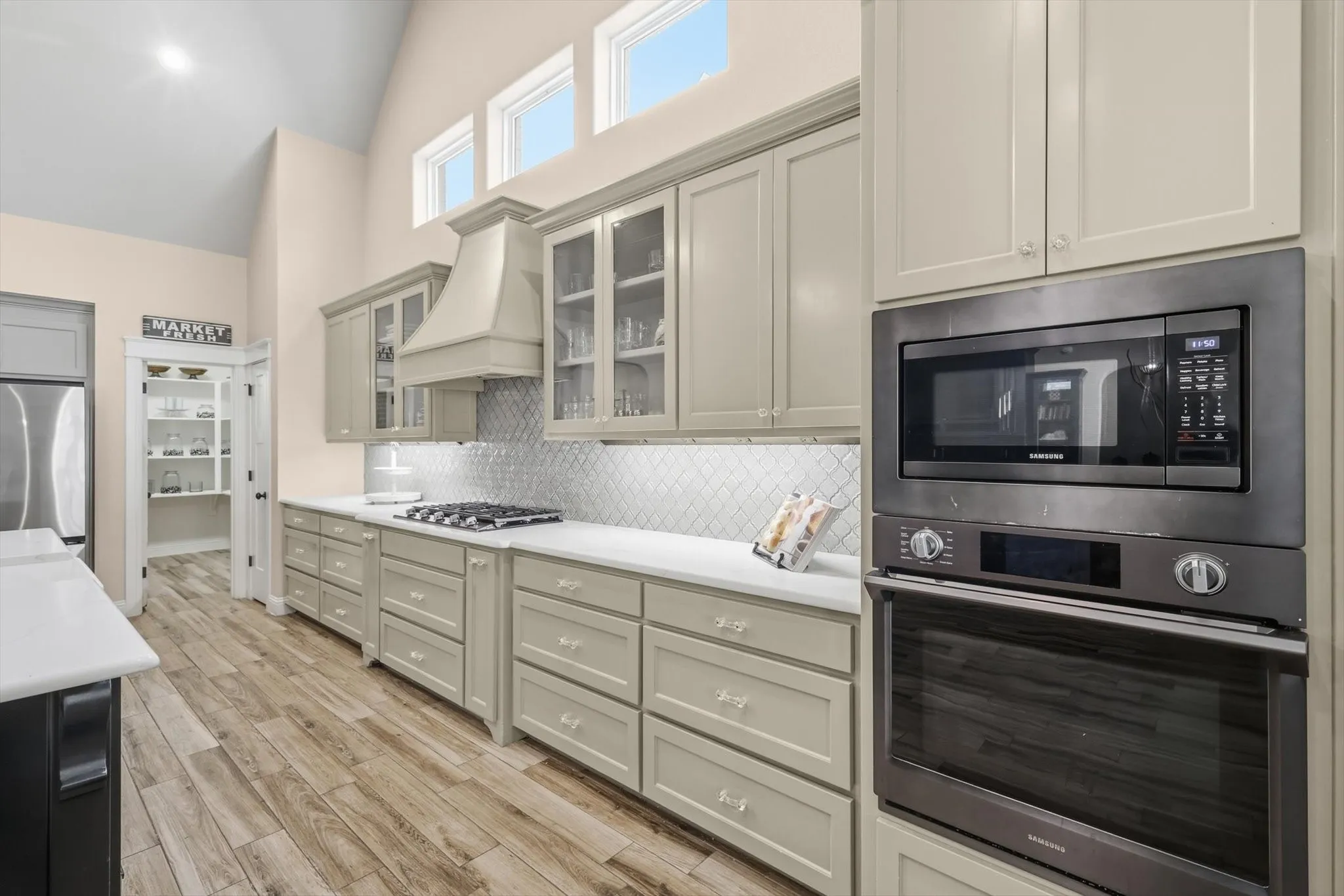 Kitchen featuring light cabinetry, wood-finish flooring, built-in stainless steel appliances, a gas cooktop, and a walk-in pantry