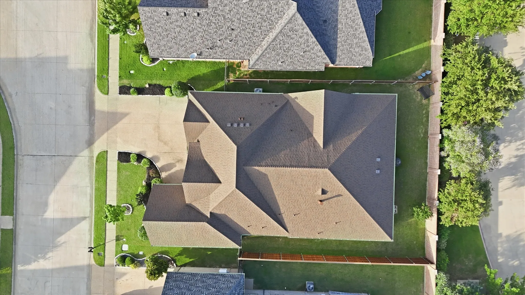 Single-story residence featuring a multi-gabled roofline, light brown shingles, and a concrete driveway