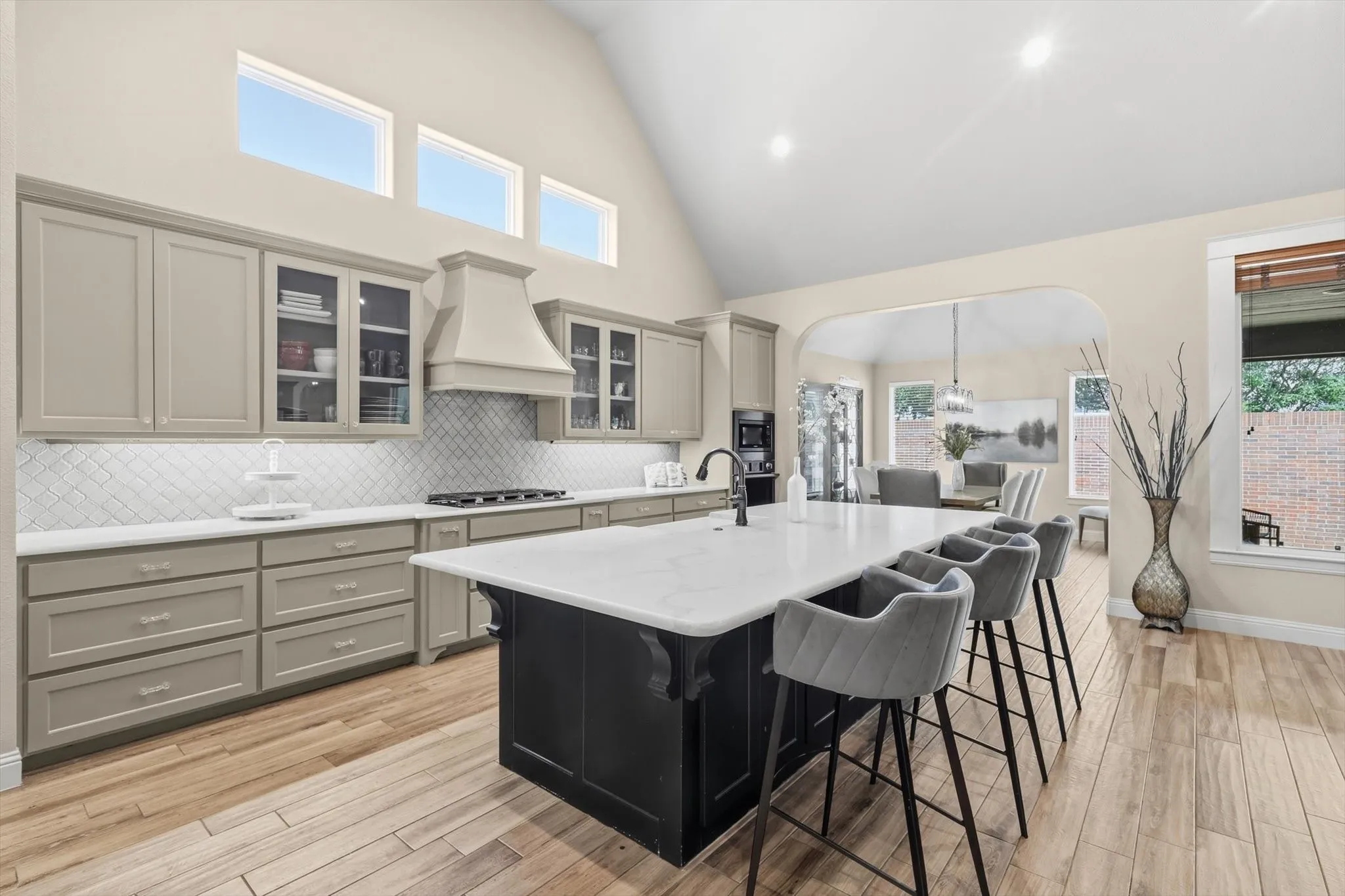 Kitchen featuring a central island with countertop seating, light-toned cabinetry, a geometric tile backsplash, and wood-finish flooring
