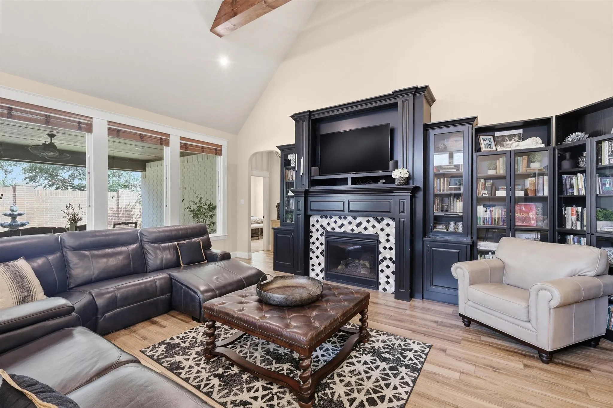 Living area featuring vaulted ceilings with exposed wood beams, a fireplace with decorative tile surround, and extensive built-in cabinetry