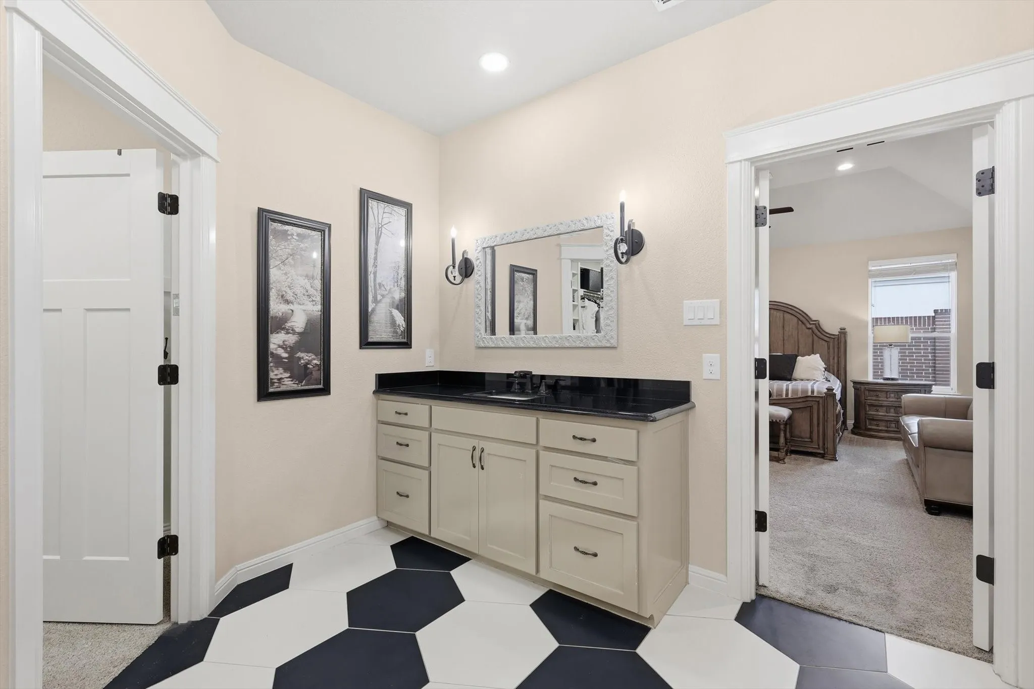 Vanity area featuring a dark countertop, undermount sink, and light-toned cabinetry