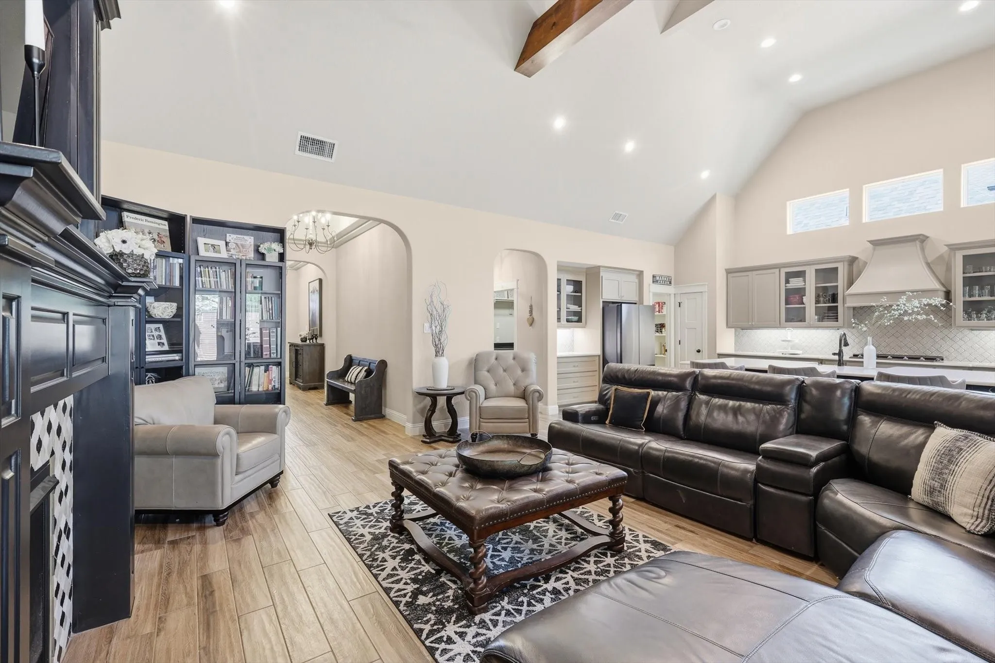 Spacious living area featuring vaulted ceilings with exposed beams, wood-finish flooring, and recessed lighting