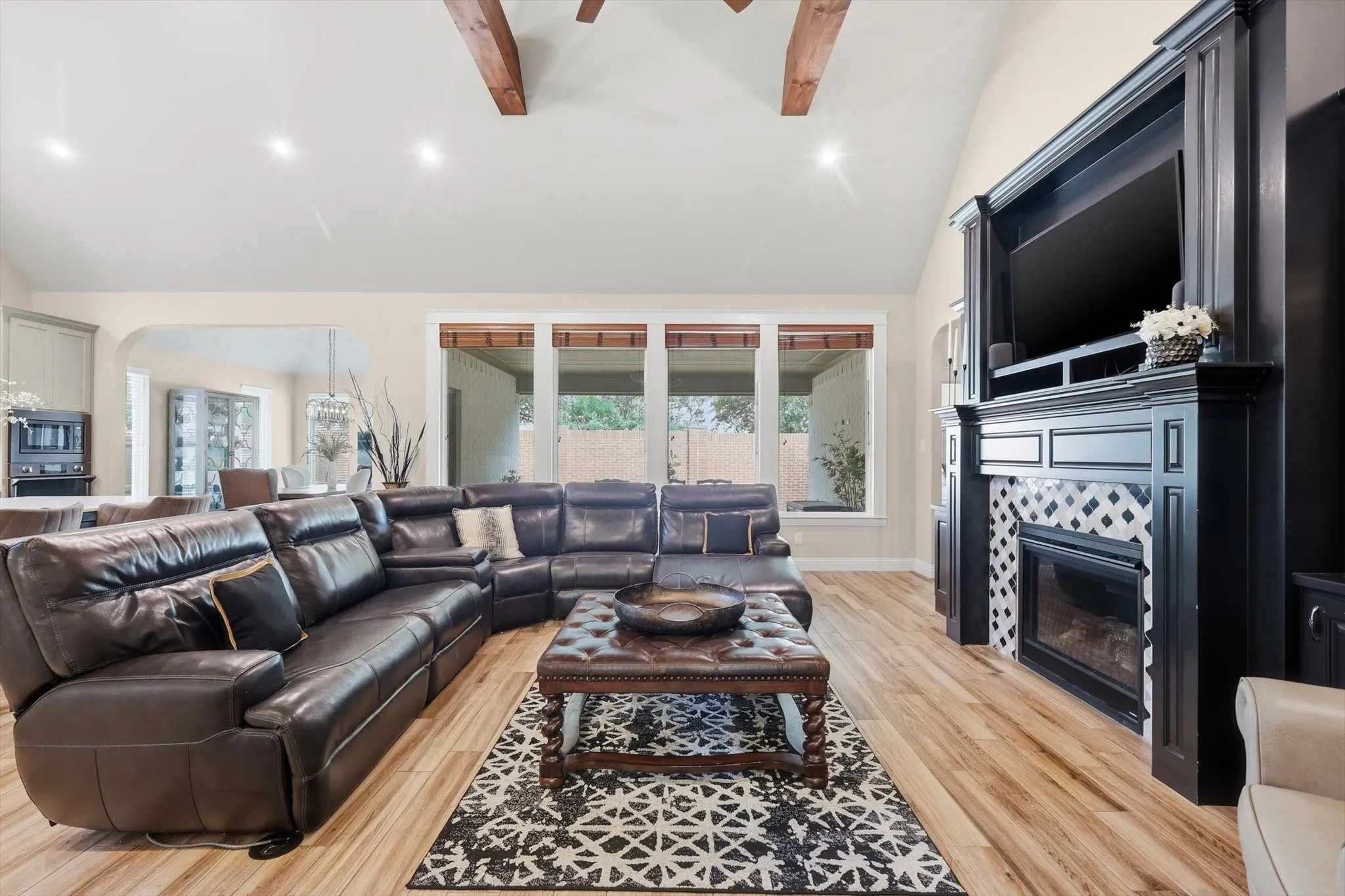 Spacious living area featuring high vaulted ceilings with exposed wood beams, recessed lighting, and wood-finish flooring