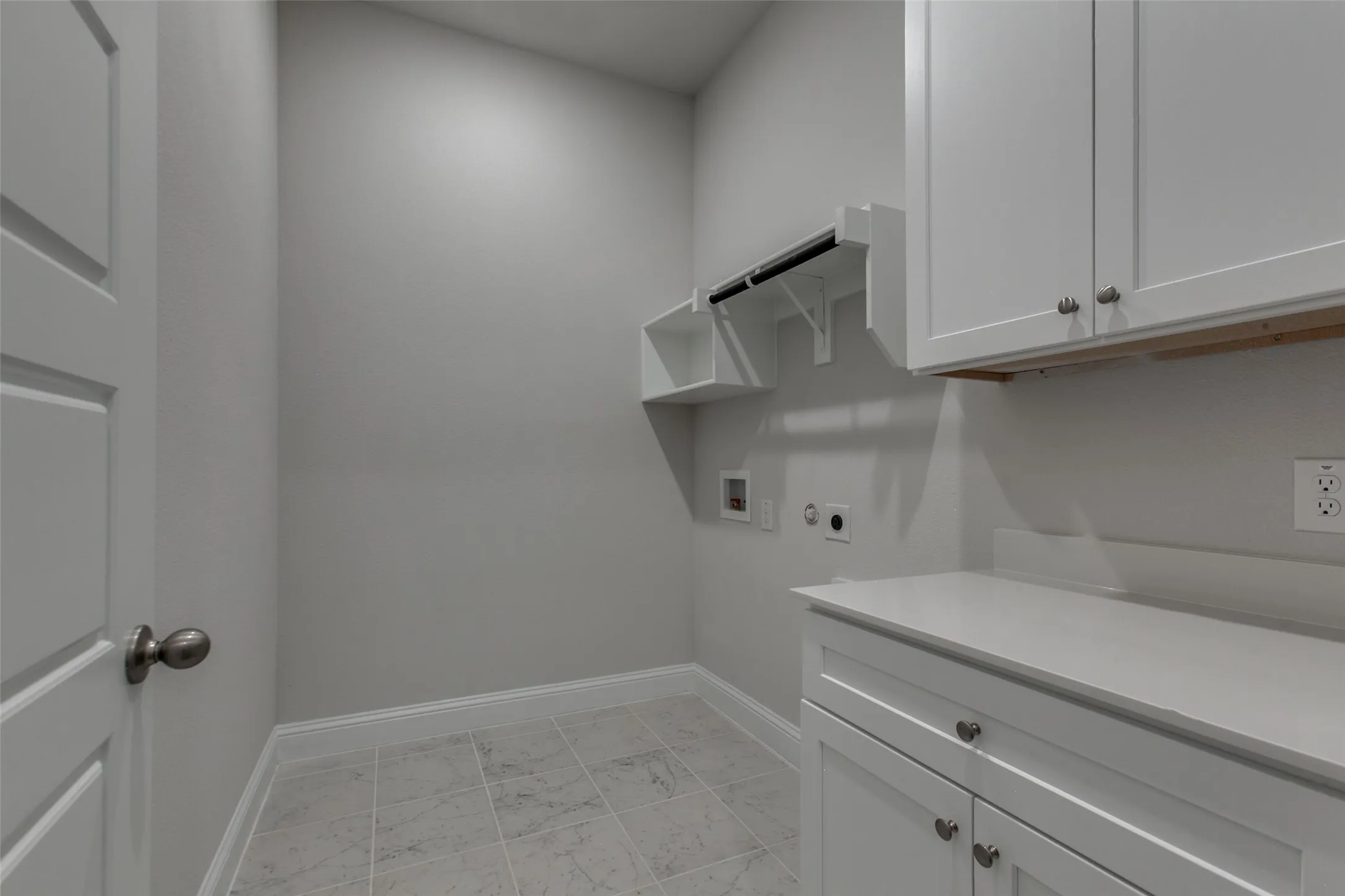 Utility room featuring a built-in counter with cabinetry, overhead storage, and tile flooring