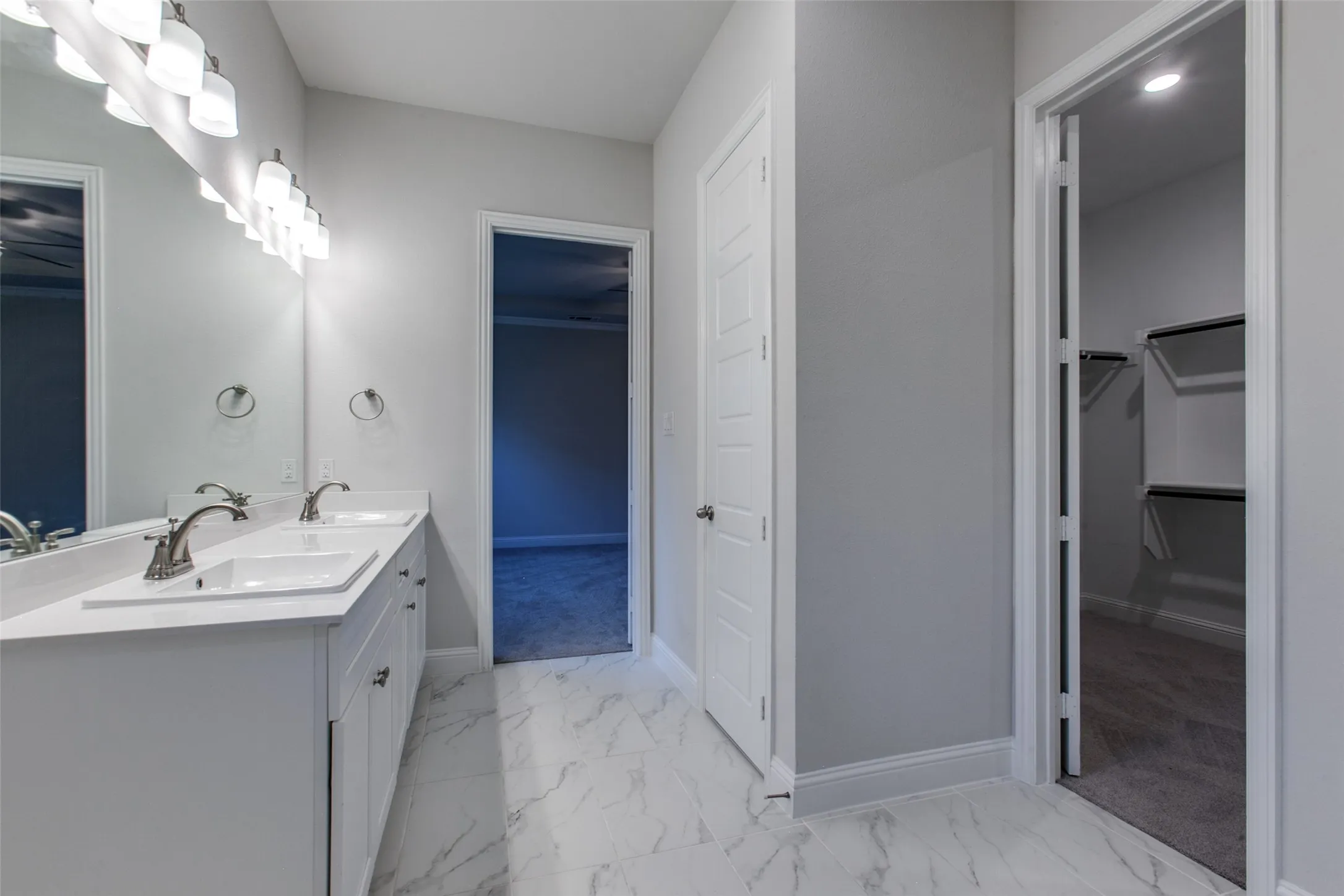 Bathroom featuring a double vanity with white cabinetry, rectangular undermount sinks, brushed nickel faucets, and a large mirror with a multi-bulb light fixture