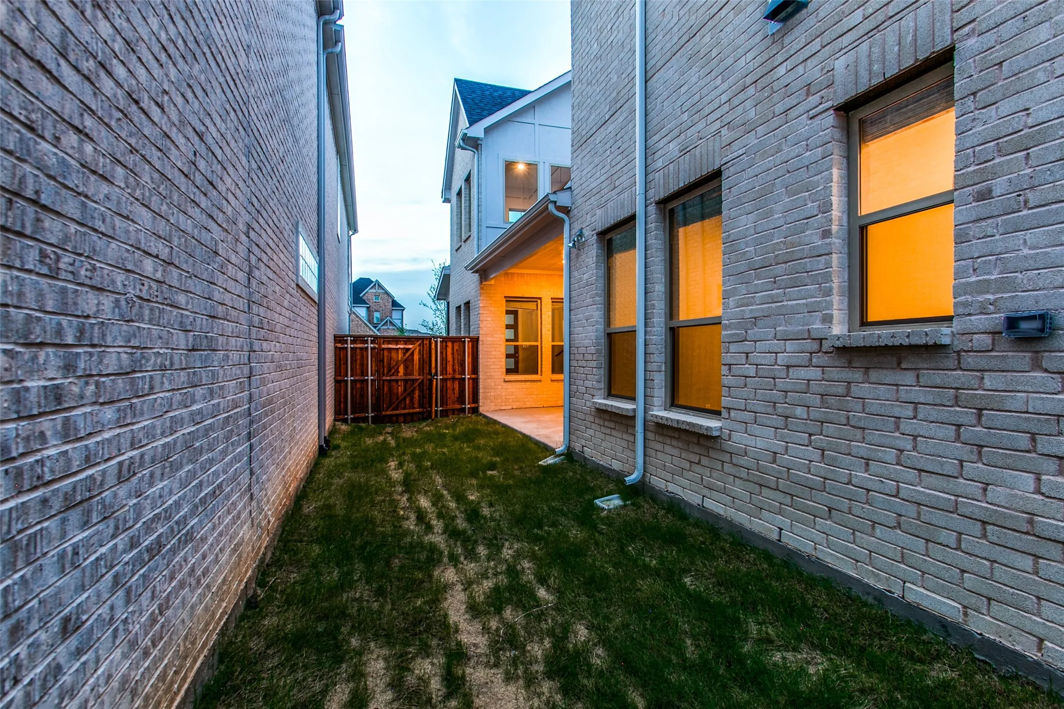 Side yard featuring a manicured lawn, full brick exterior, a paved patio, and a wood privacy fence