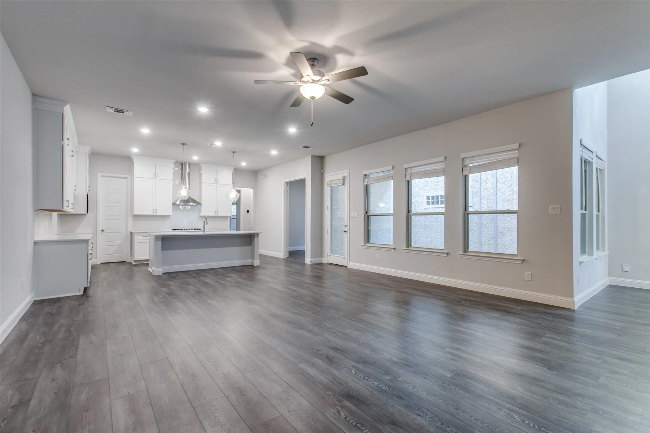 Open concept living area featuring dark wood-finish flooring, a contemporary ceiling fan with integrated lighting, and multiple recessed light fixtures
