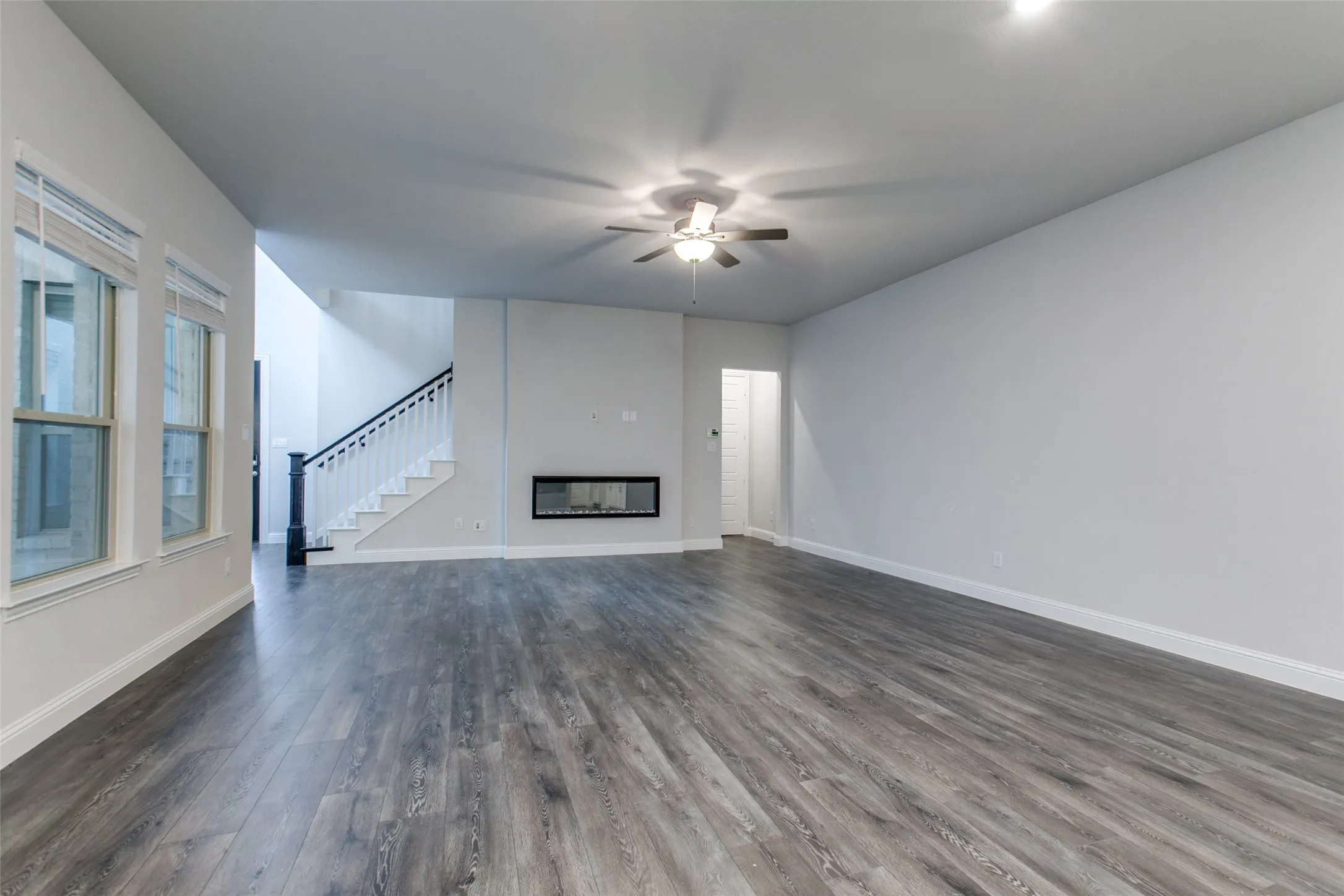 Spacious living area featuring wood-finish flooring, a contemporary linear fireplace, and multiple large windows