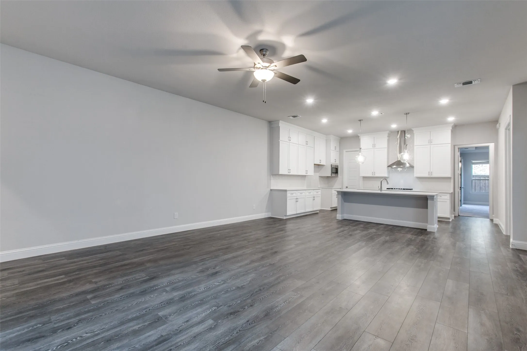 Spacious open-concept living area featuring wood-finish flooring, a ceiling fan, and recessed lighting