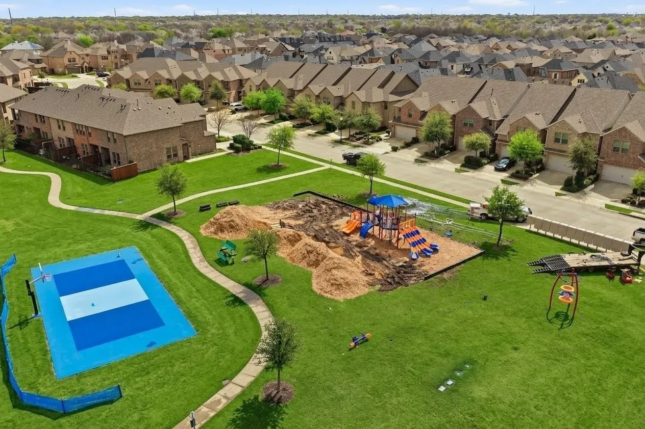 Aerial view of a residential community featuring brick-exterior homes with attached garages