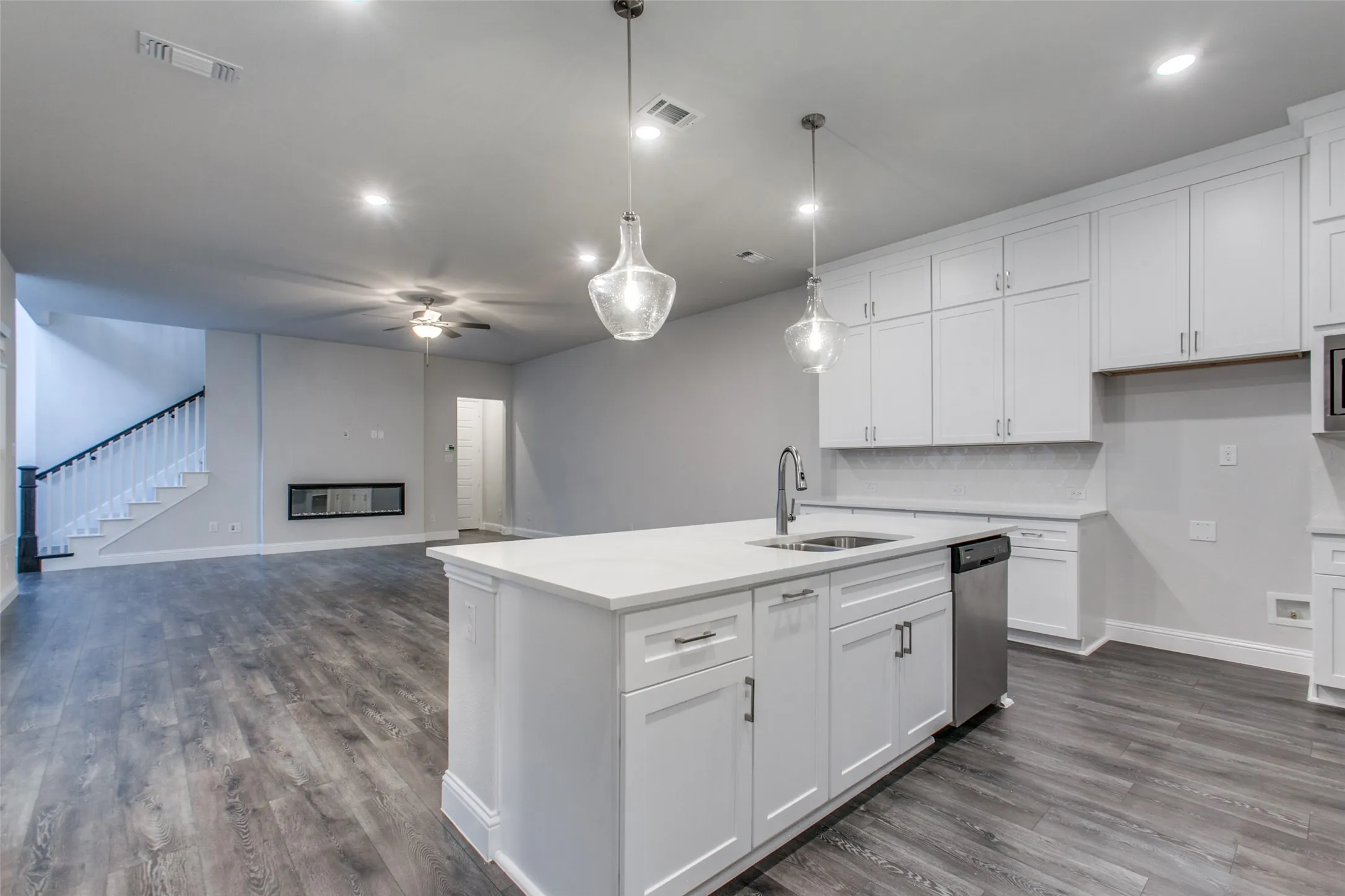 Kitchen island with white shaker cabinetry, quartz countertop, and stainless steel sink with a gooseneck faucet