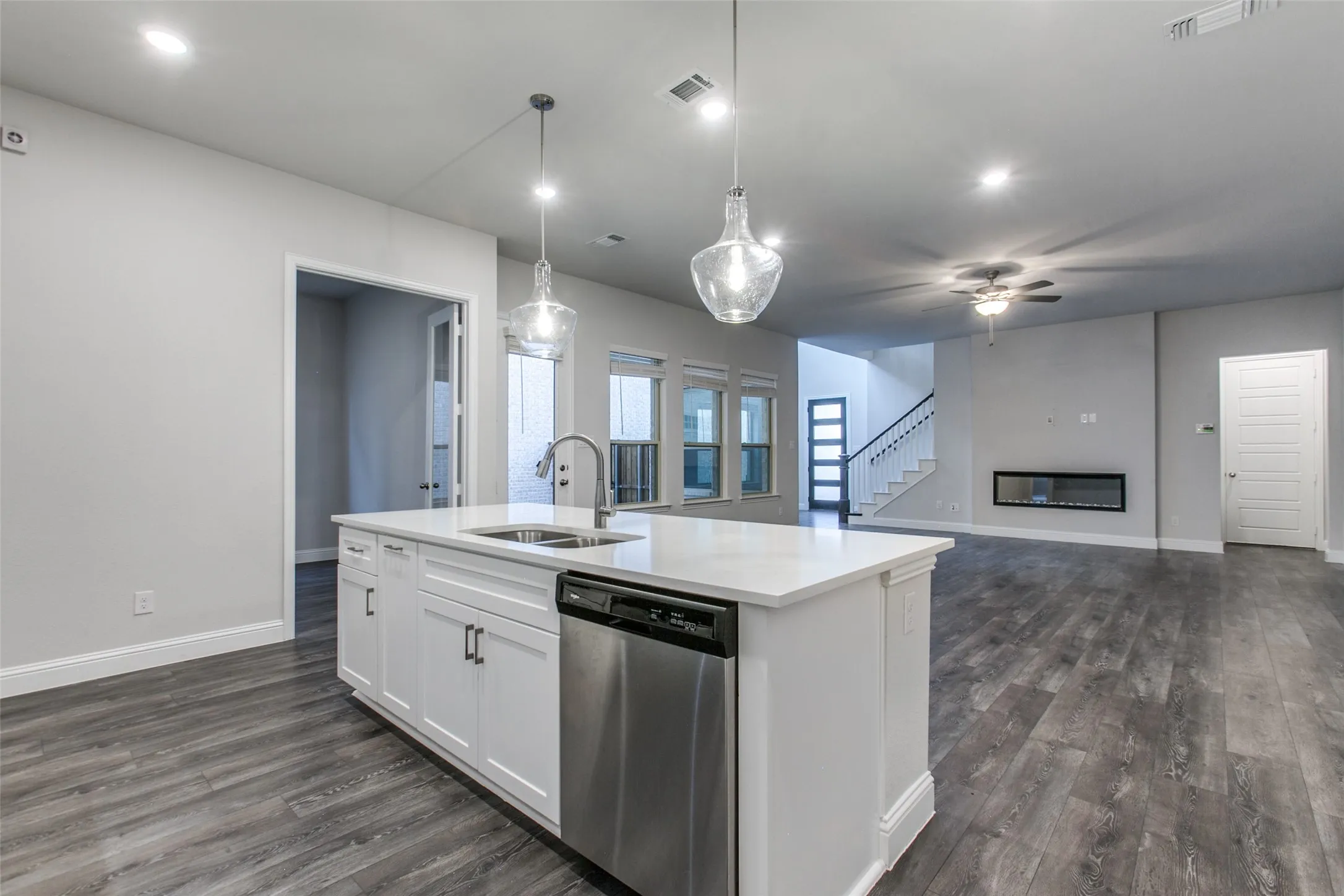 Kitchen island with white shaker cabinetry, stainless steel dishwasher, and a dual basin sink with a gooseneck faucet