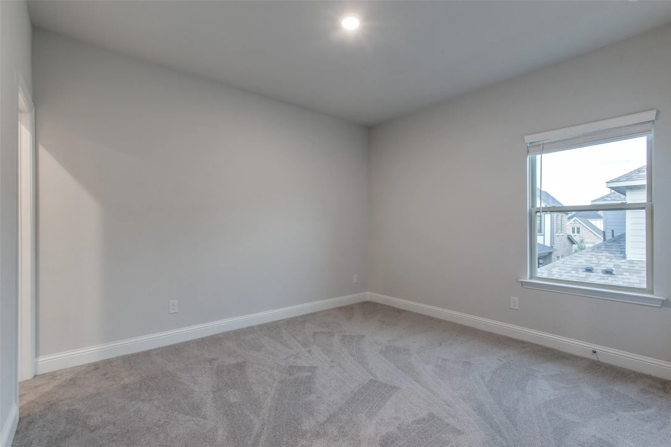 Carpeted room with a single window, recessed lighting, and crisp white baseboards
