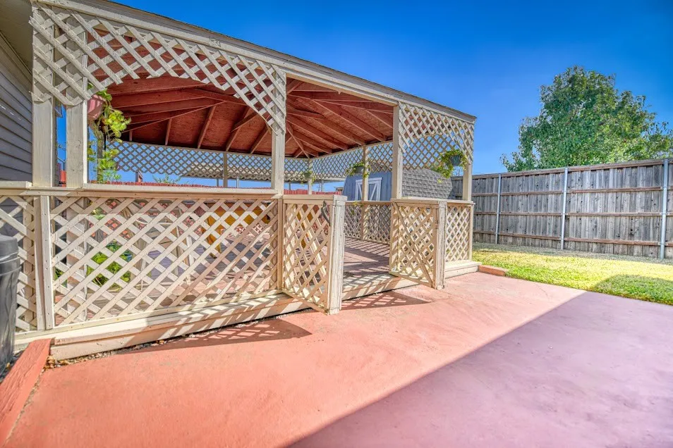 Lattice-panel covered patio with a wooden slatted roof, providing an outdoor living area