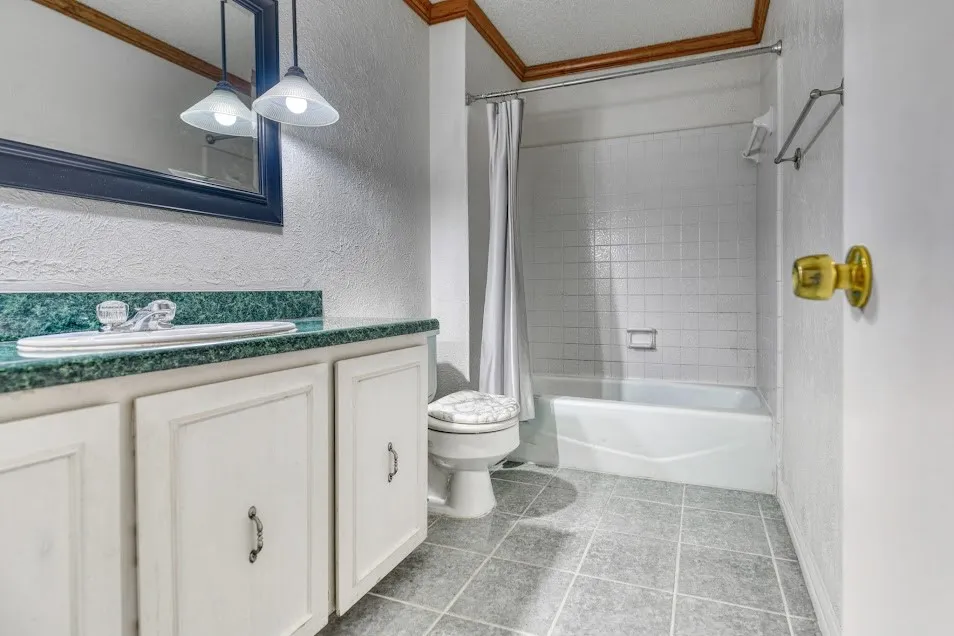 Bathroom featuring a vanity with a green countertop, undermount sink, white cabinetry, tile flooring, and a tub/shower combination with white subway tile surround