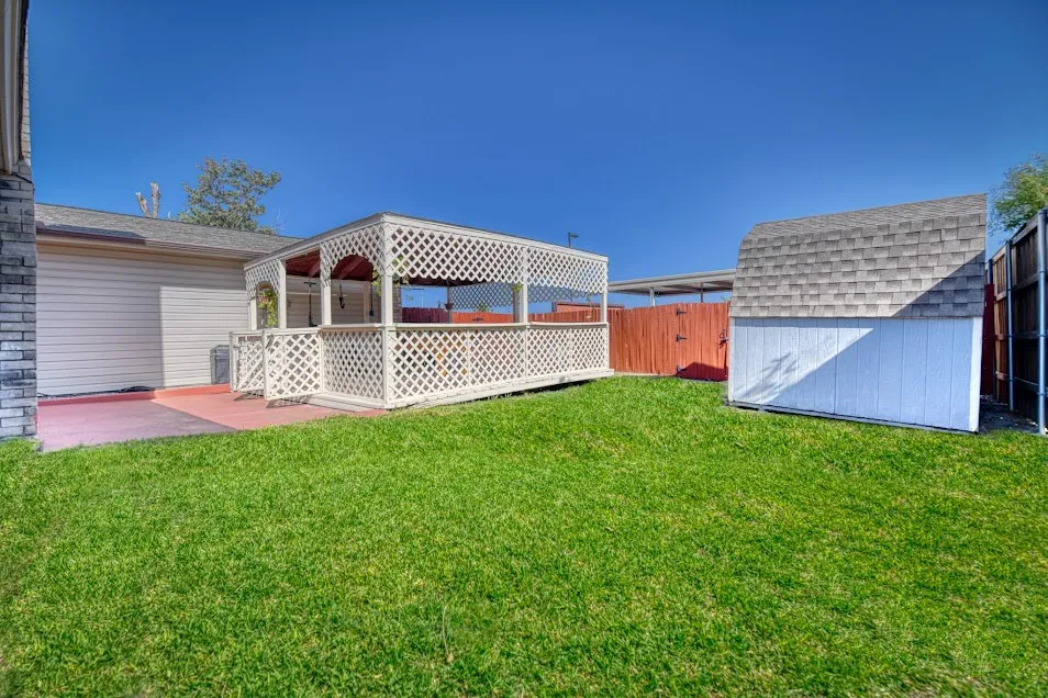 Expansive backyard featuring a gazebo, concrete patio, storage shed, and wood fencing
