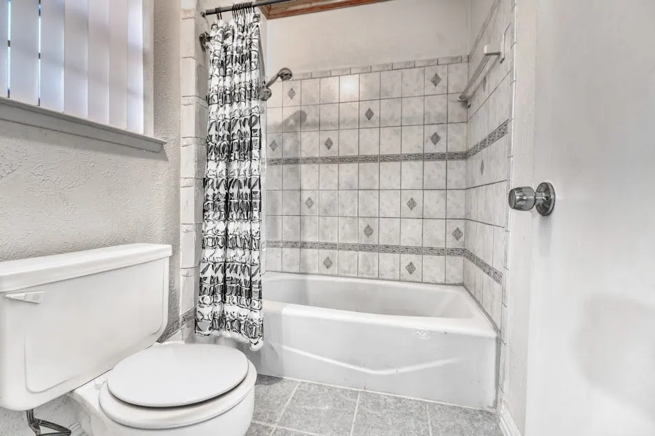 White tile-surround bathtub and shower with patterned accent tiles