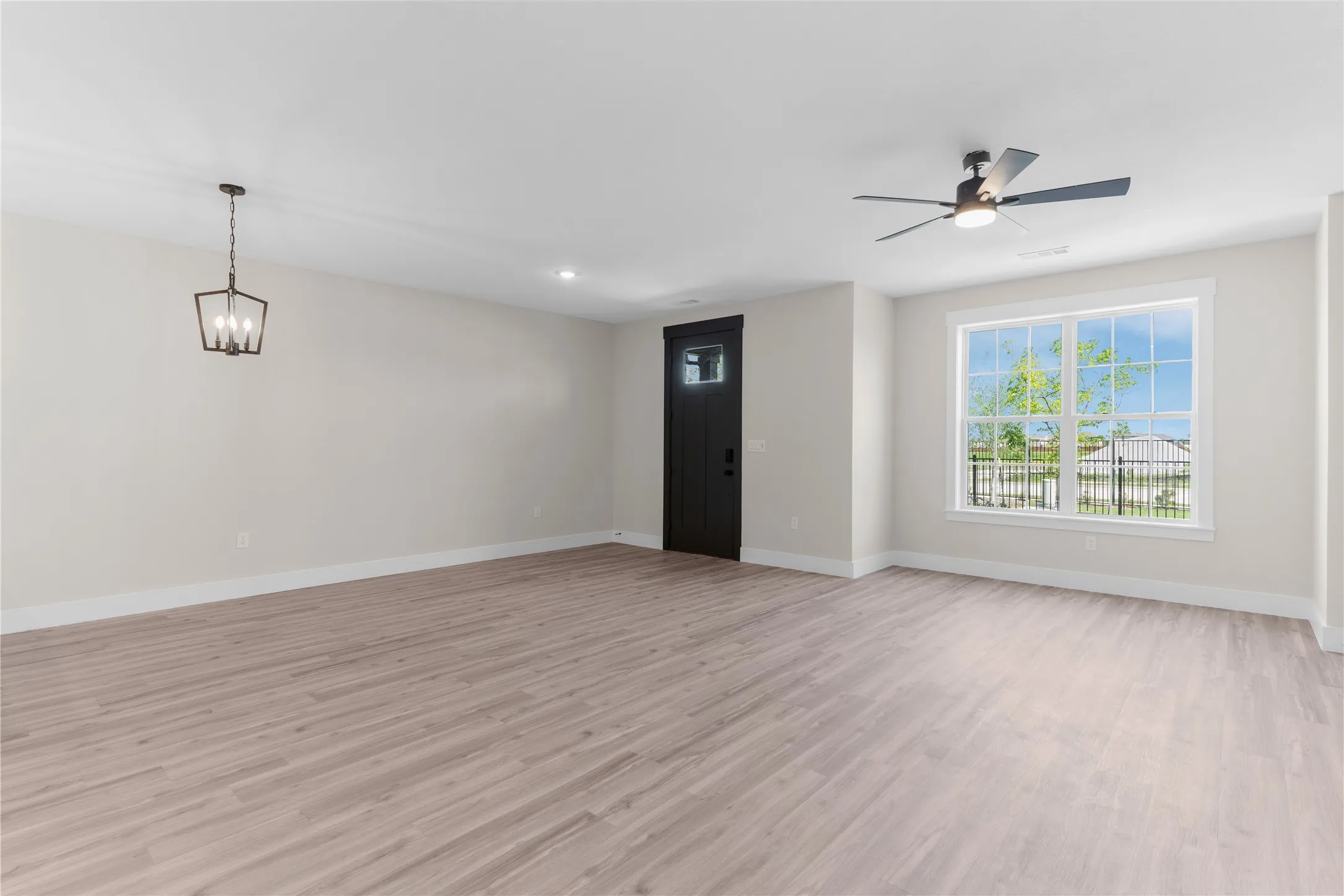 Spacious room featuring wood-finish flooring, a contemporary ceiling fan, and a four-light pendant fixture