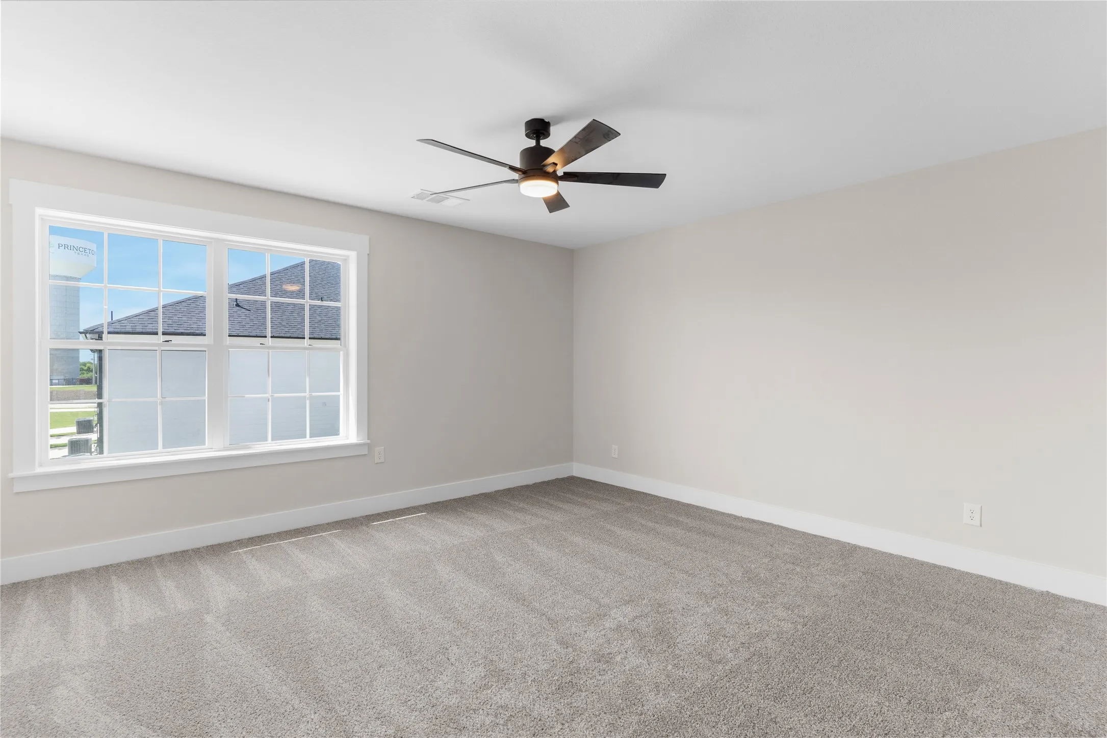 Spacious room featuring neutral carpeting, light-toned walls, and a modern ceiling fan with integrated lighting