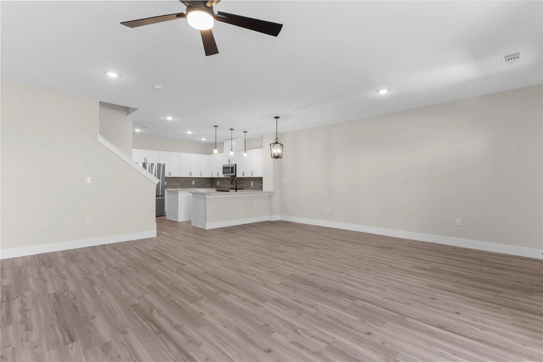 Open-concept living space featuring wood-finish flooring, recessed lighting, and a contemporary ceiling fan