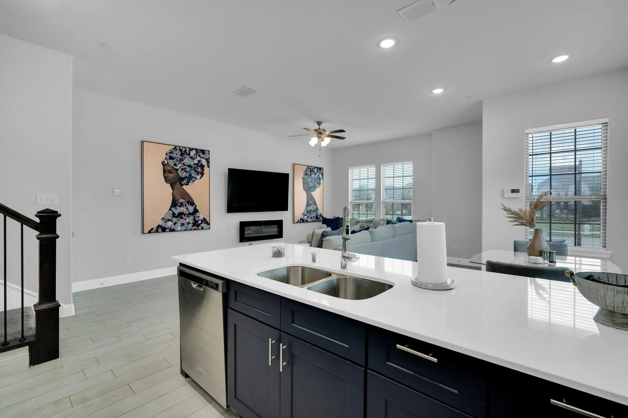 Kitchen island featuring a stainless steel double basin sink, white stone countertop, and dark blue cabinetry with brushed nickel hardware