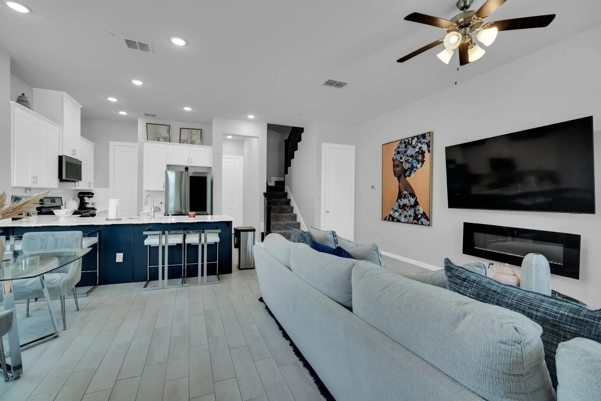 Open-concept living space featuring wood-finish flooring, a contemporary electric fireplace, and recessed lighting