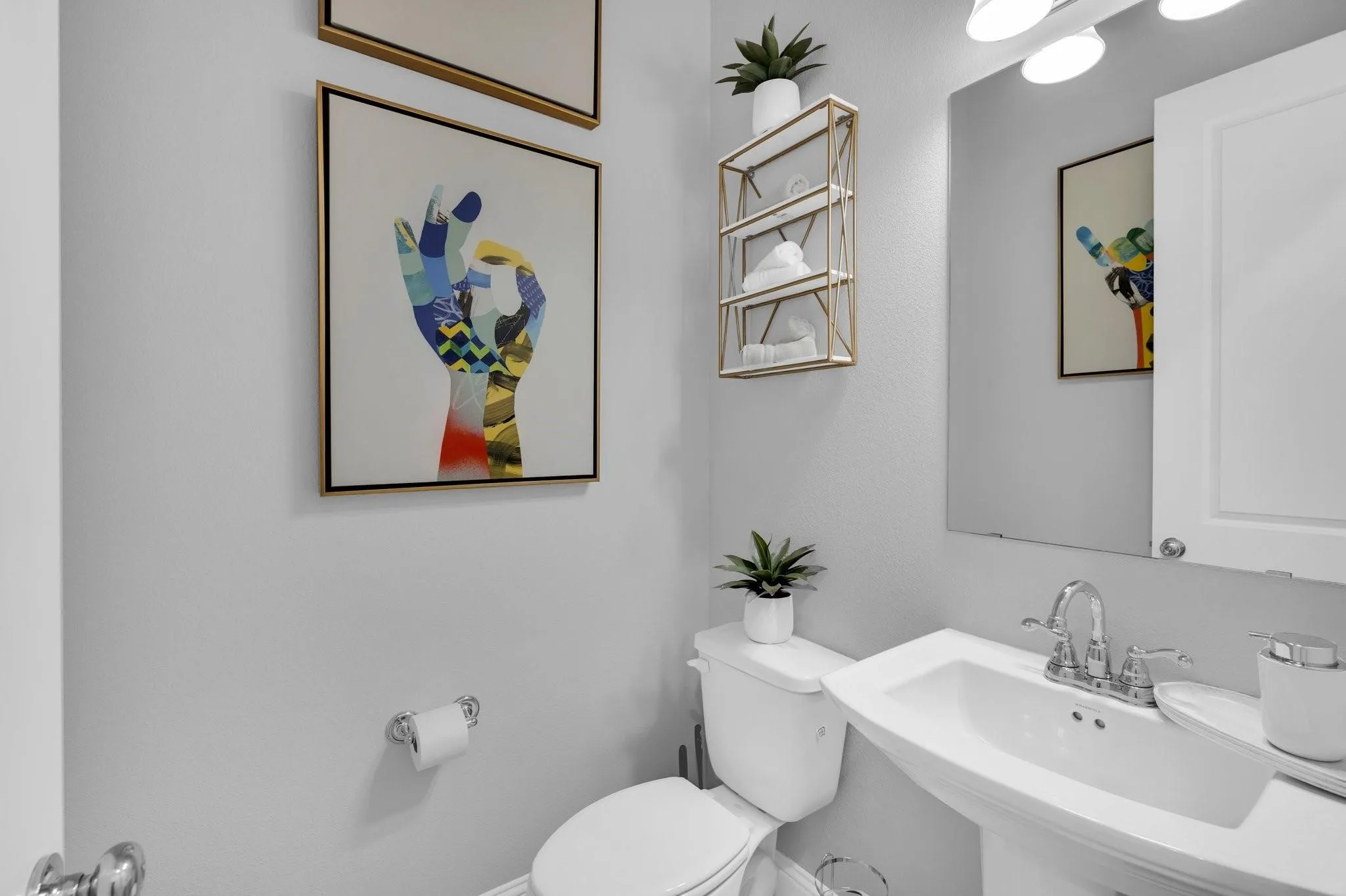 Pedestal sink with chrome fixtures and overhead vanity lighting