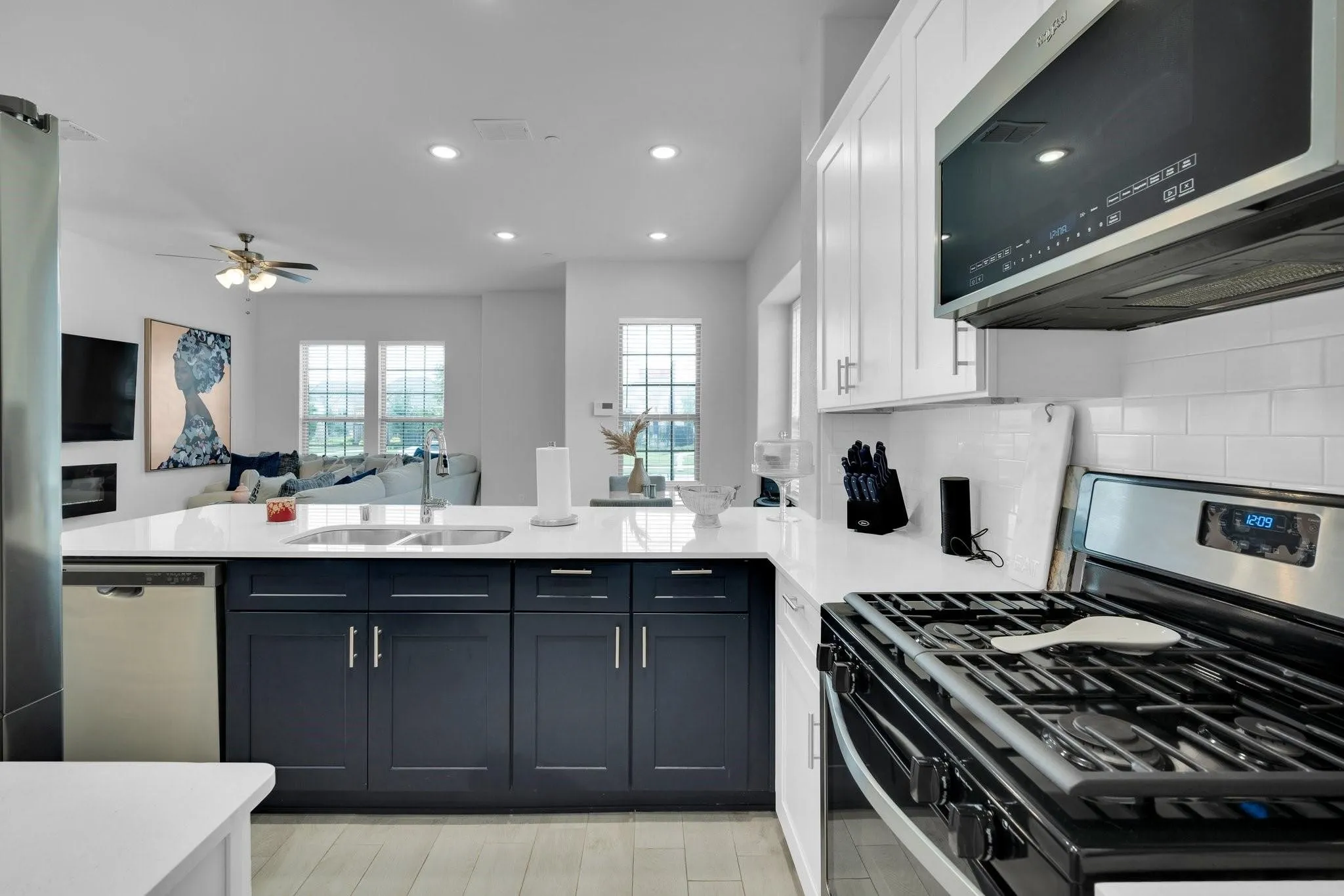 Contemporary kitchen featuring white shaker upper cabinetry and dark lower cabinetry with brushed nickel hardware